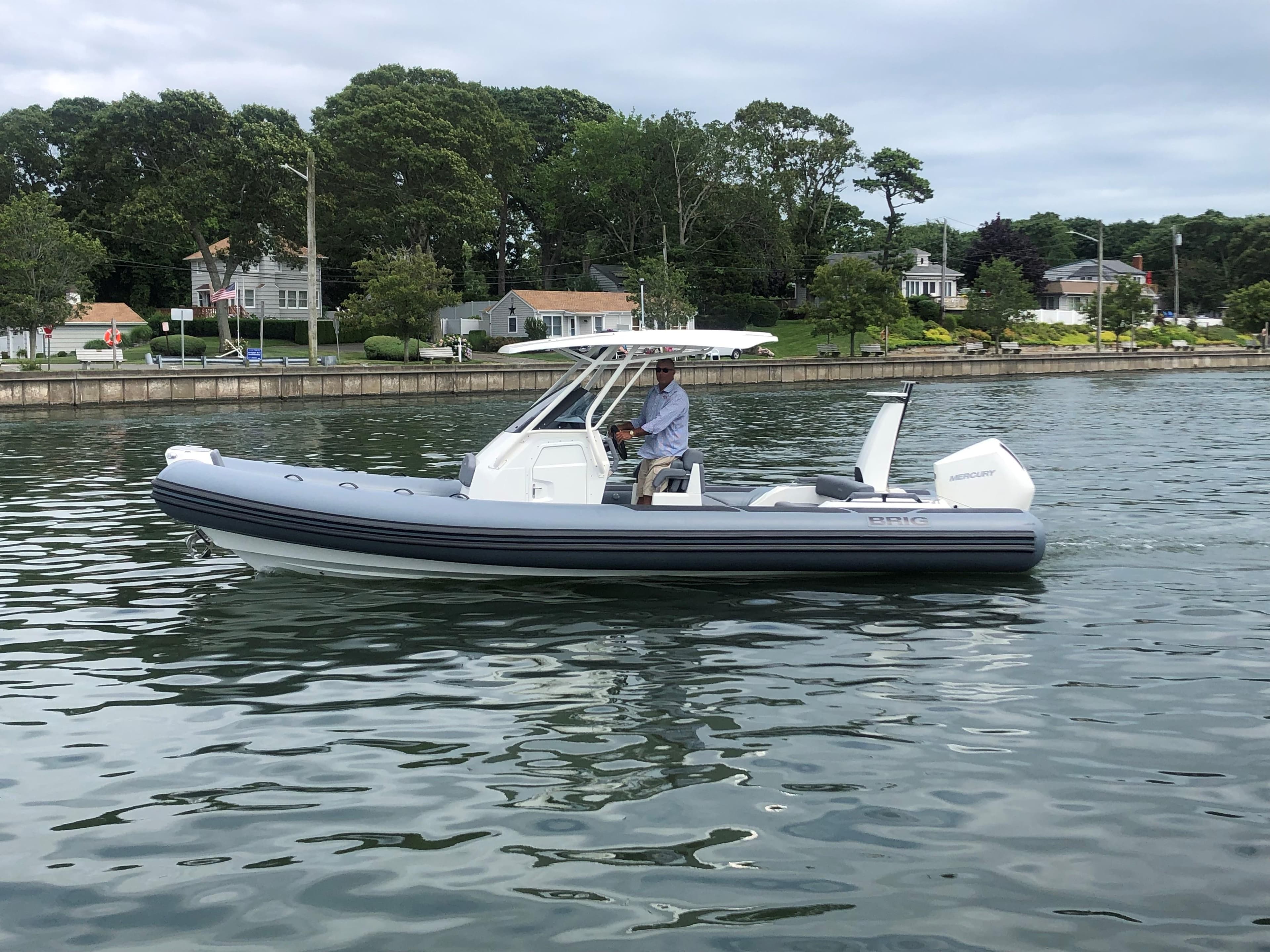 2024 Brig Eagle 8 boat cruising on a calm lake near a residential area.