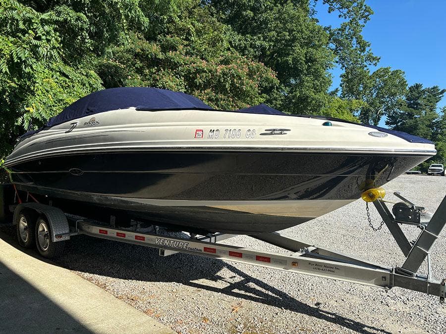 2007 Sea Ray 220 Sundeck boat on a trailer, covered and parked outdoors.