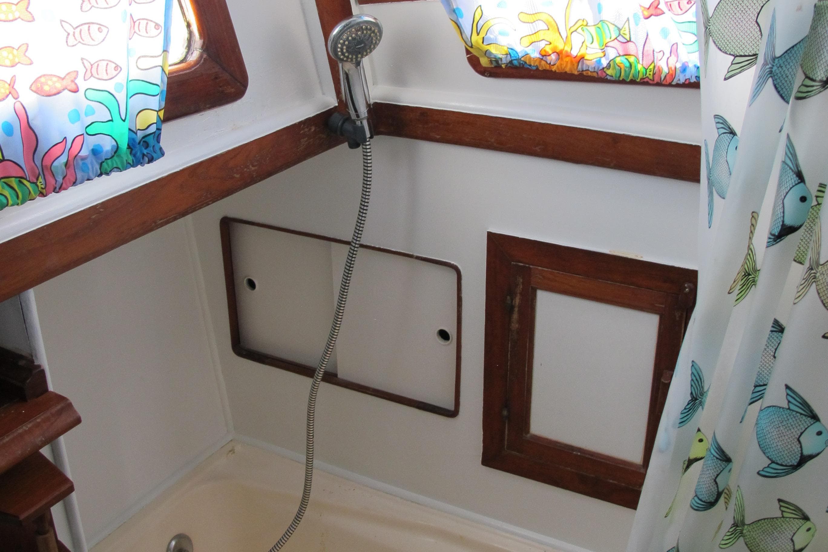 1981 Albin 36 boat bathroom with colorful fish-themed curtains and wooden accents.