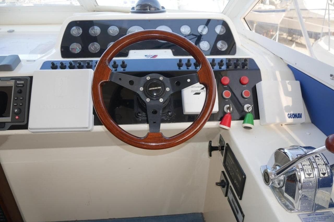 Cockpit of 1994 Fairline Phantom 37 yacht with wooden steering wheel and control panel.