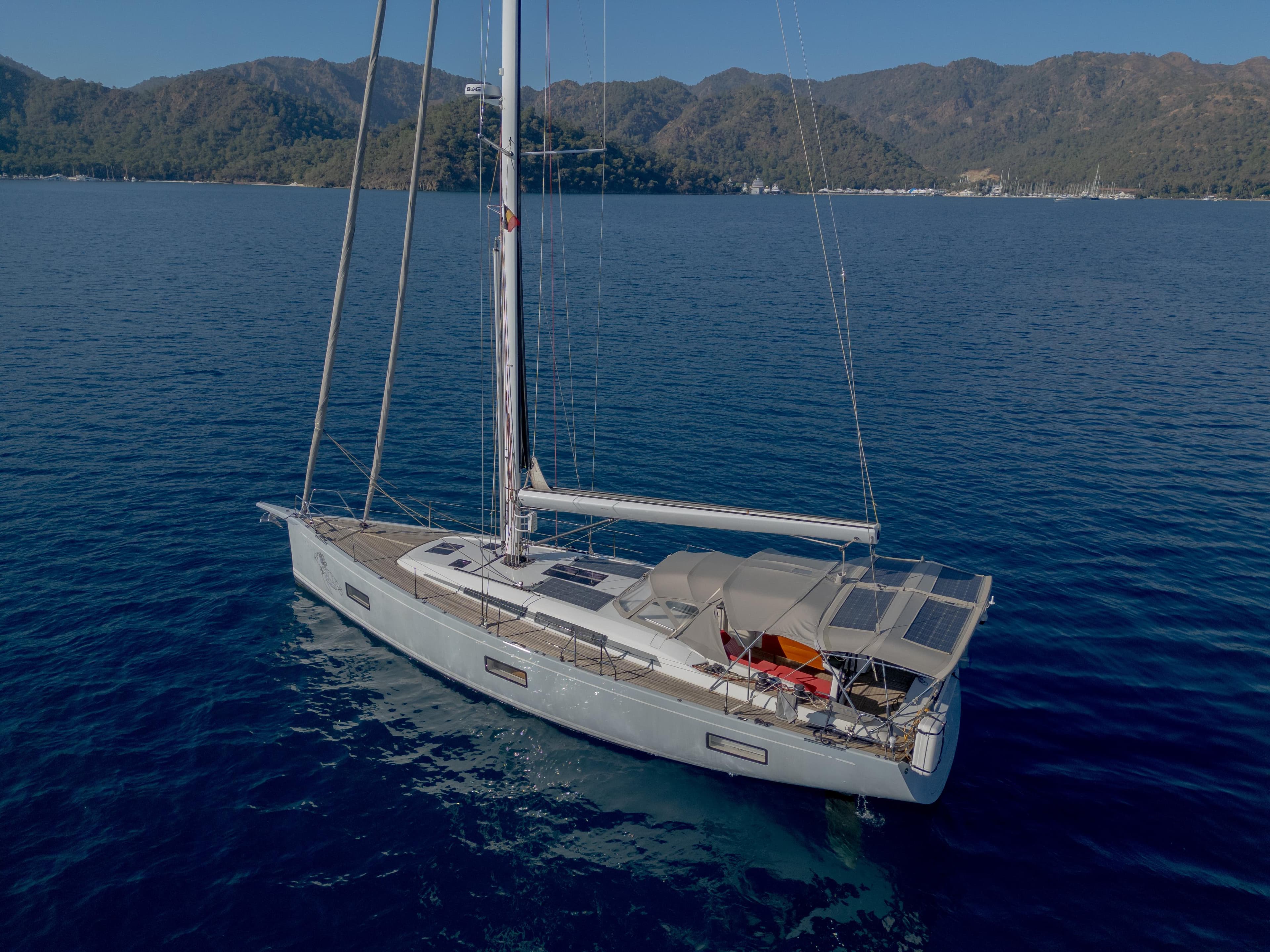 Nautor Swan 48 sailboat, 2020 model, cruising on serene blue waters with mountainous backdrop.