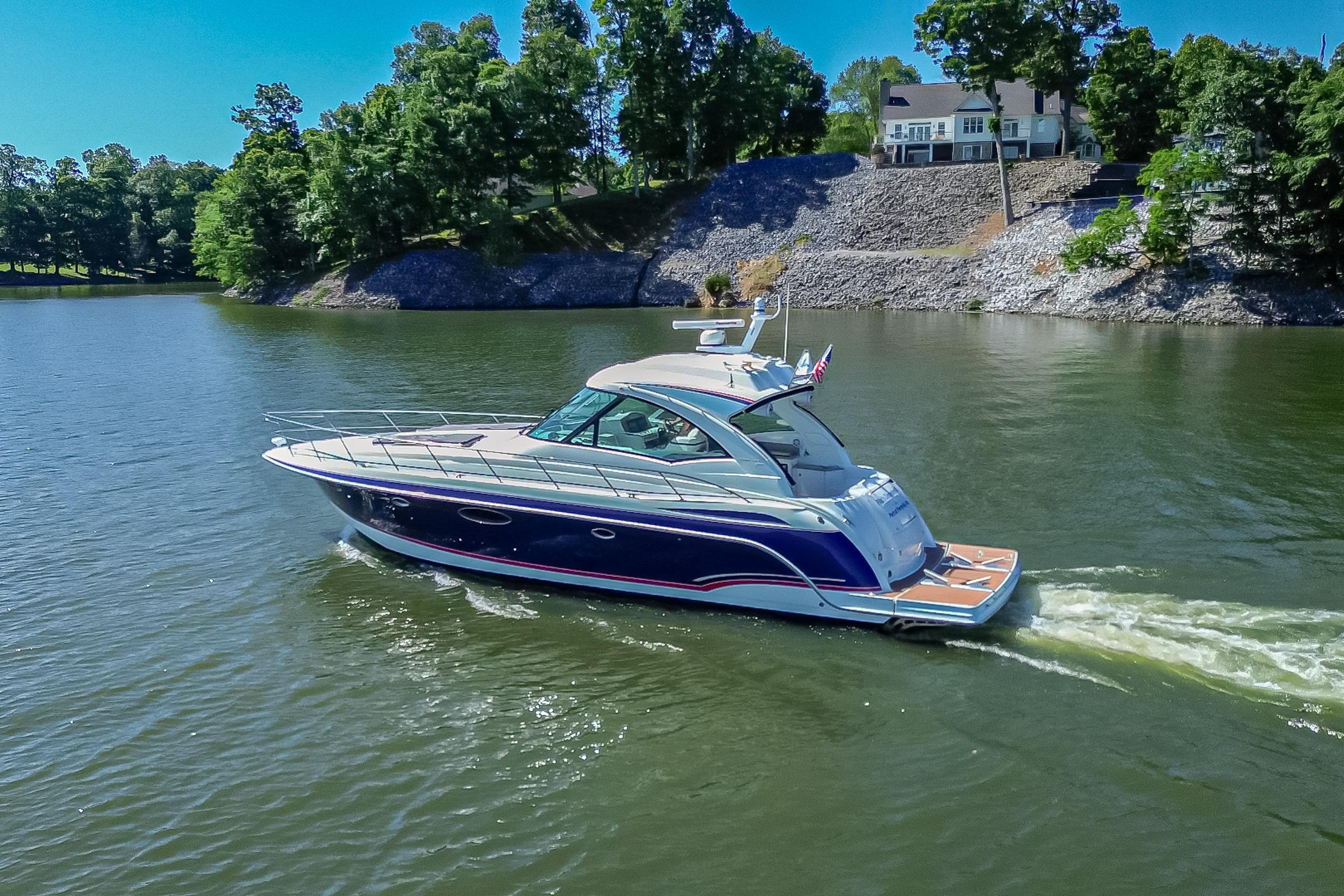 2008 Formula 45 Yacht cruising on a serene lake with lush greenery.