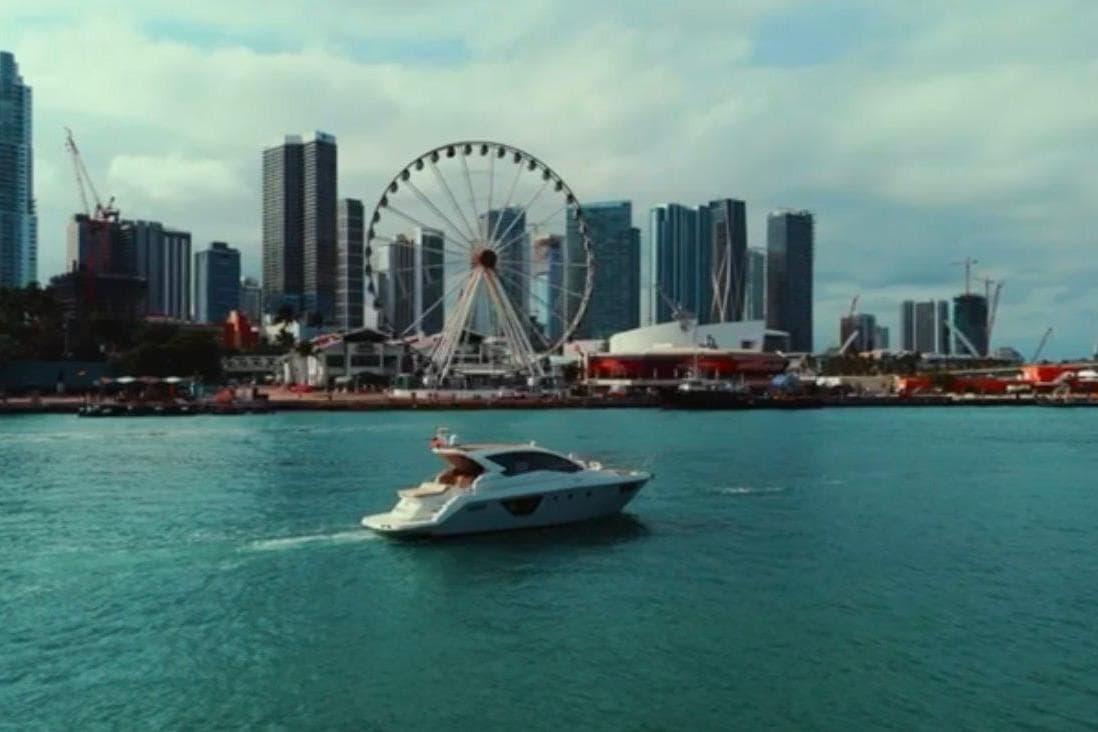 Cranchi M44 HT yacht cruising near city skyline and Ferris wheel, 2013 model.