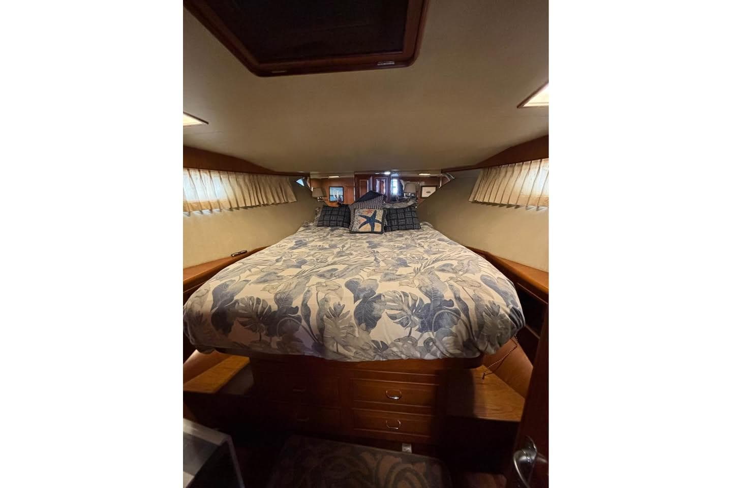 Cozy bedroom interior of 1990 Ocean Alexander 420 Sport Sedan yacht with floral bedding.