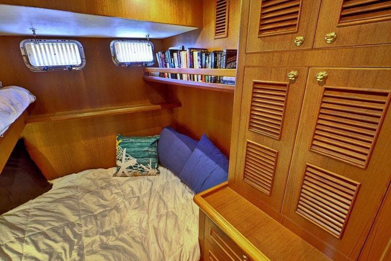 Cozy cabin interior of 2016 North Pacific 45 Pilothouse with books and bedding.
