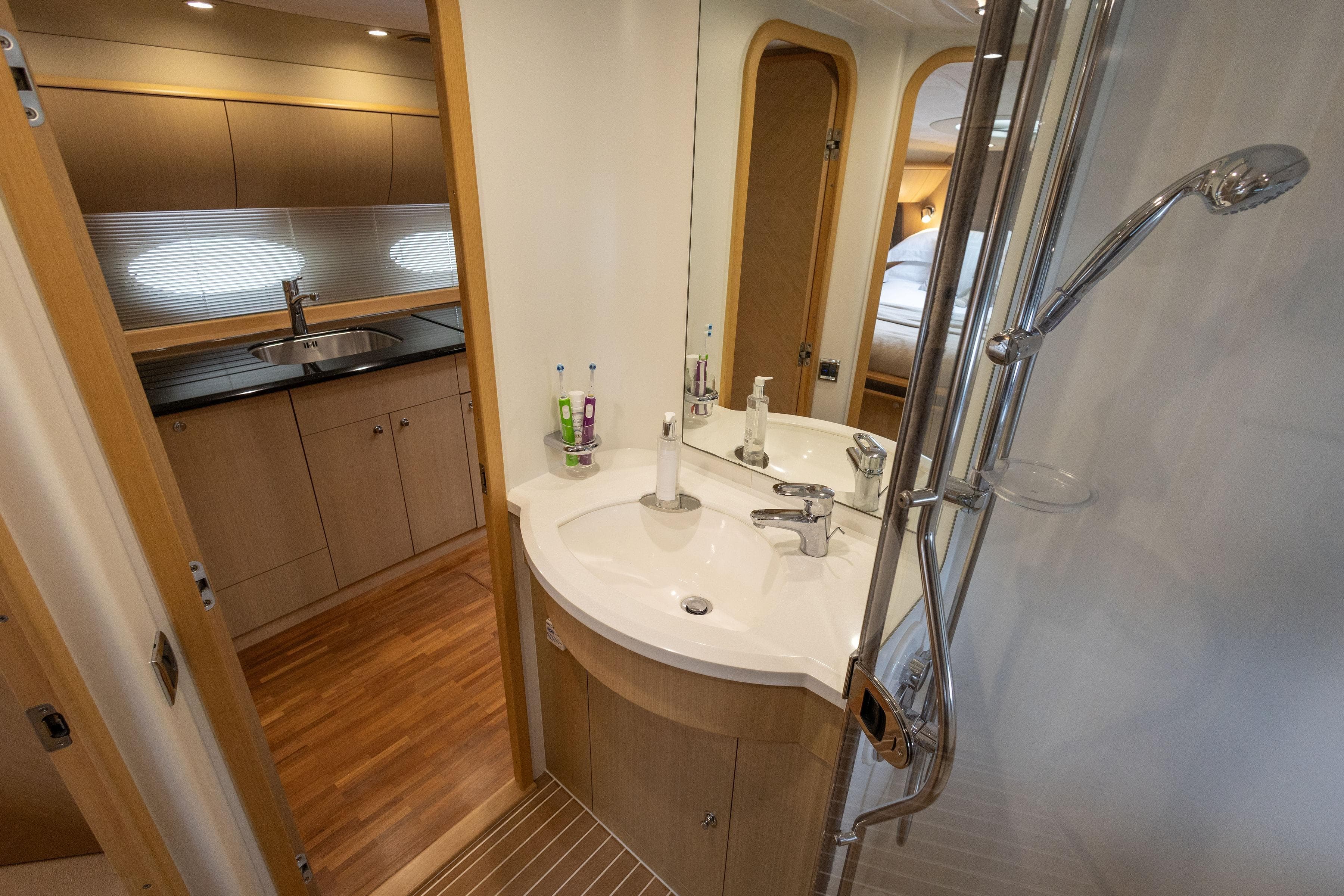Luxurious bathroom and kitchenette in 2009 Princess V58 yacht, featuring modern fixtures and wood accents.