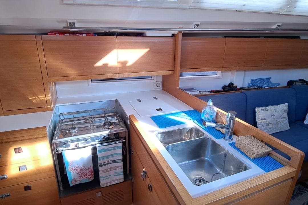 Interior of 2019 Salona 380 yacht kitchen with stove, sink, and wooden cabinetry.