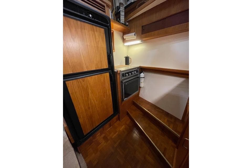 1984 Egg Harbor 33 Convertible yacht interior kitchen with wooden cabinetry and appliances.