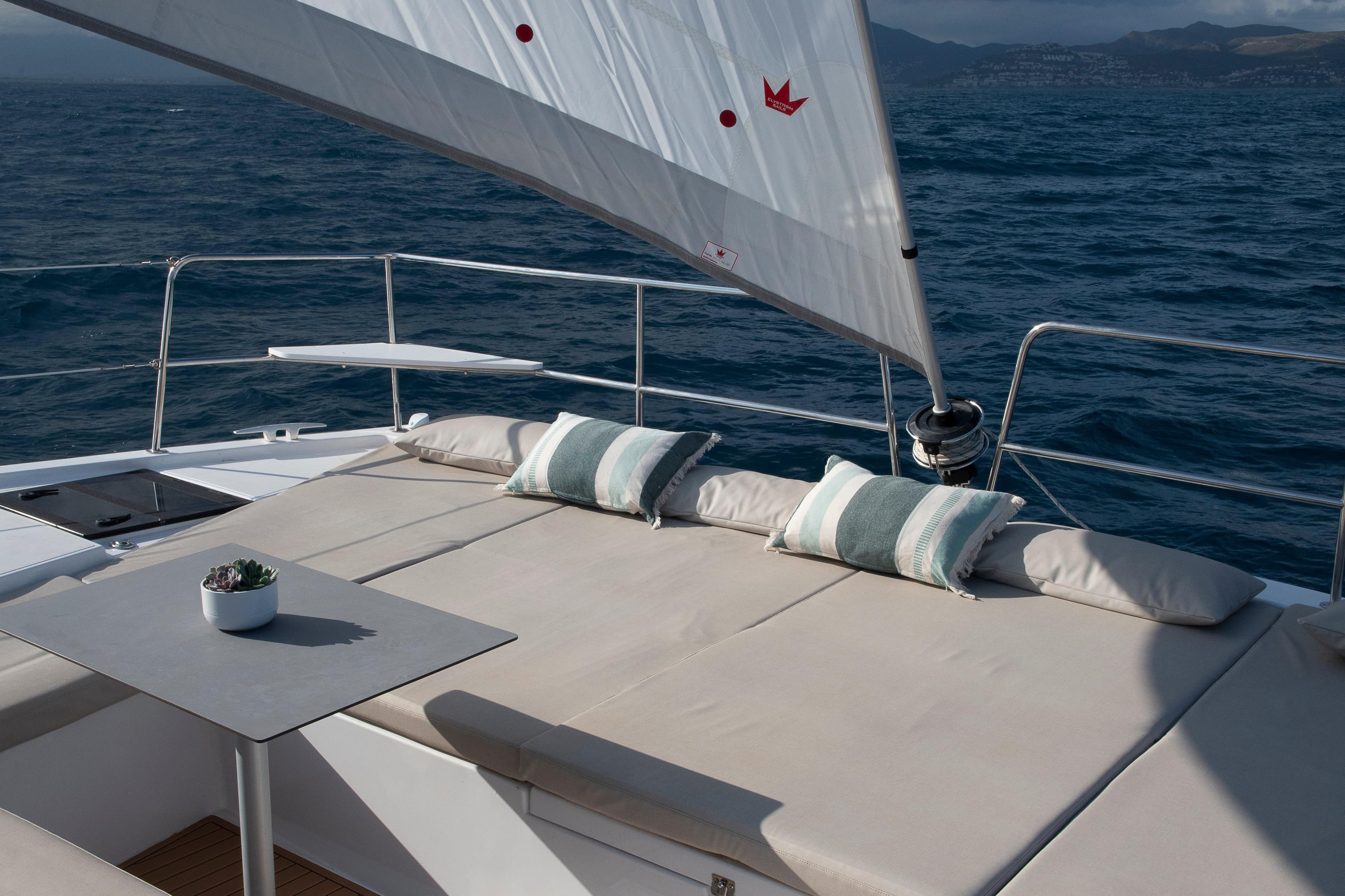 Luxurious 2024 Bali CATSMART yacht deck with cushions, table, and sail on open sea.
