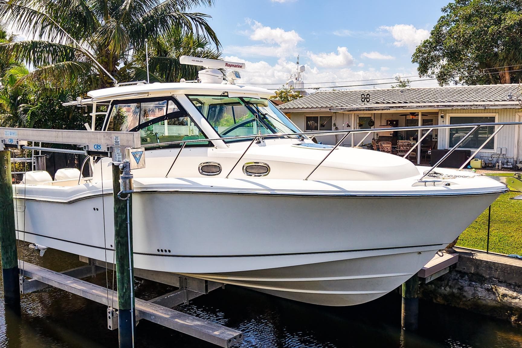 2018 Boston Whaler 315 Conquest boat docked near a house with palm trees.