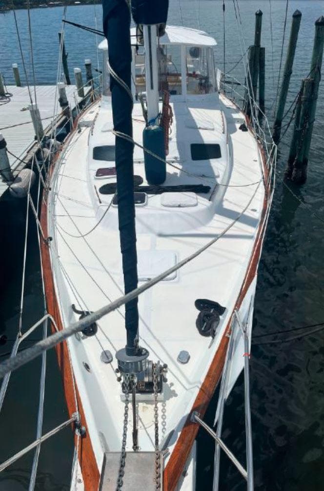Irwin 54 sailboat, 1990 model, docked at marina with wooden trim and white deck.