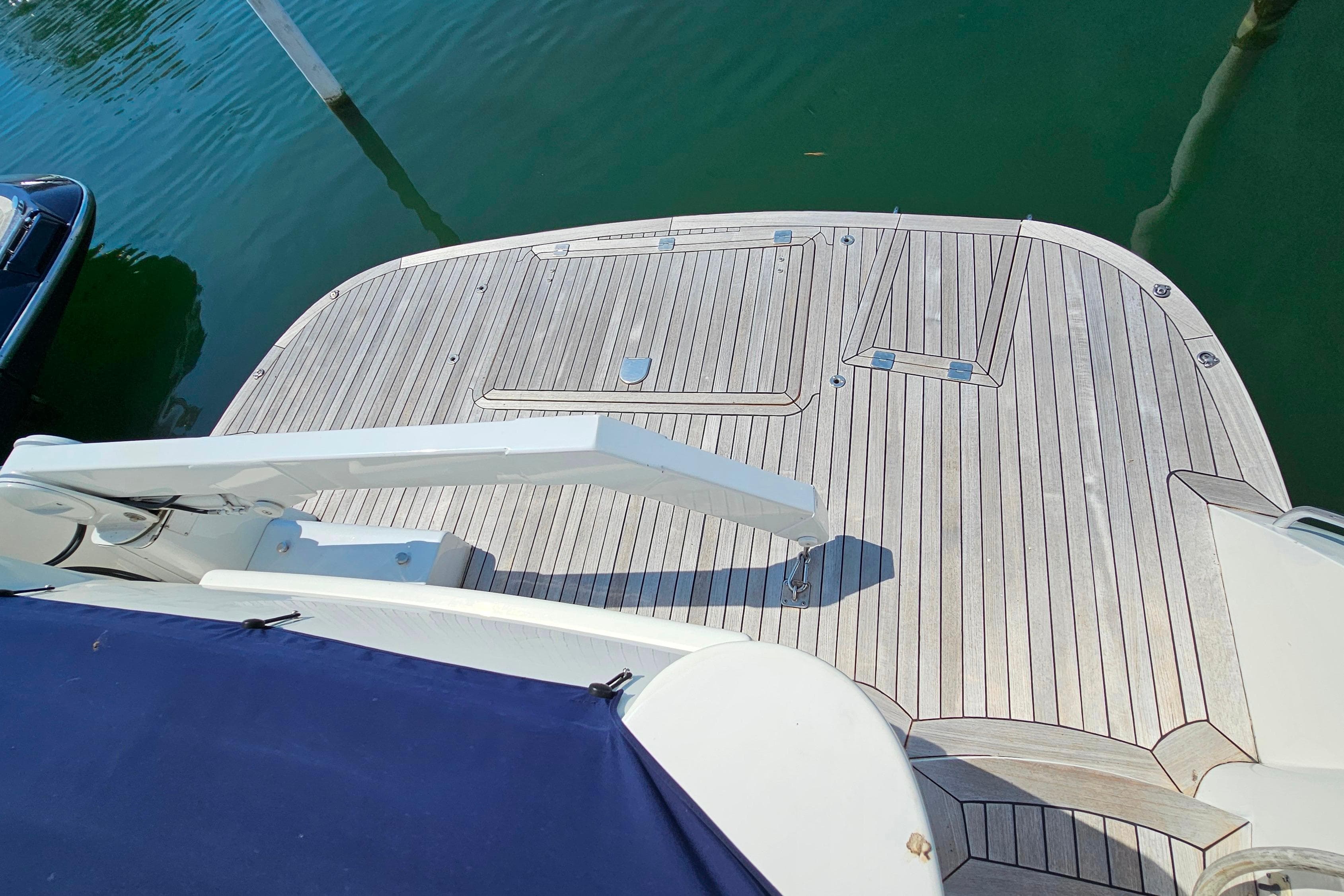 Sunseeker Manhattan 62 yacht deck, 1998 model, with wooden finish and water backdrop.