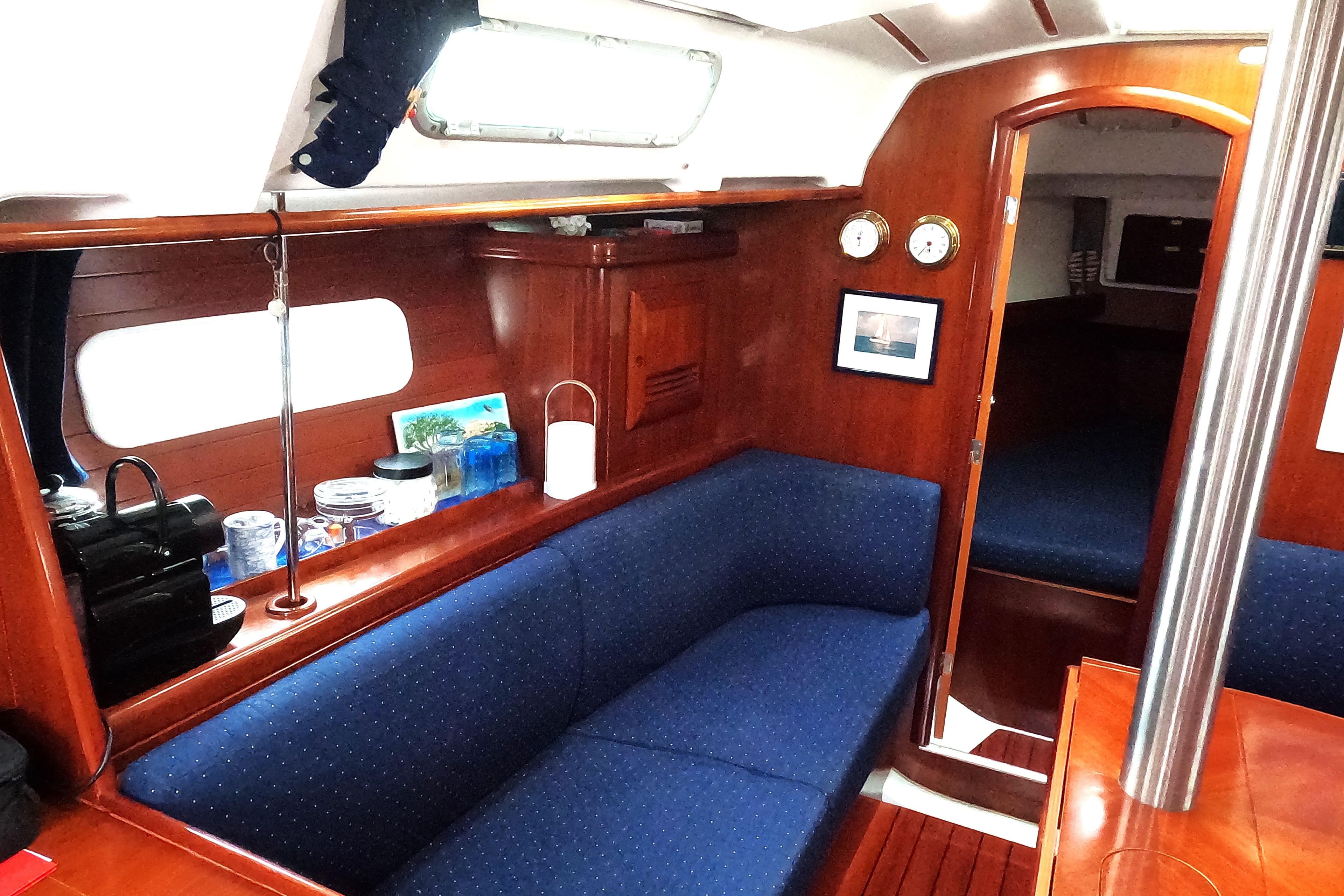 Interior of 2003 Beneteau Oceanis Clipper 361 yacht with blue seating and wooden finishes.