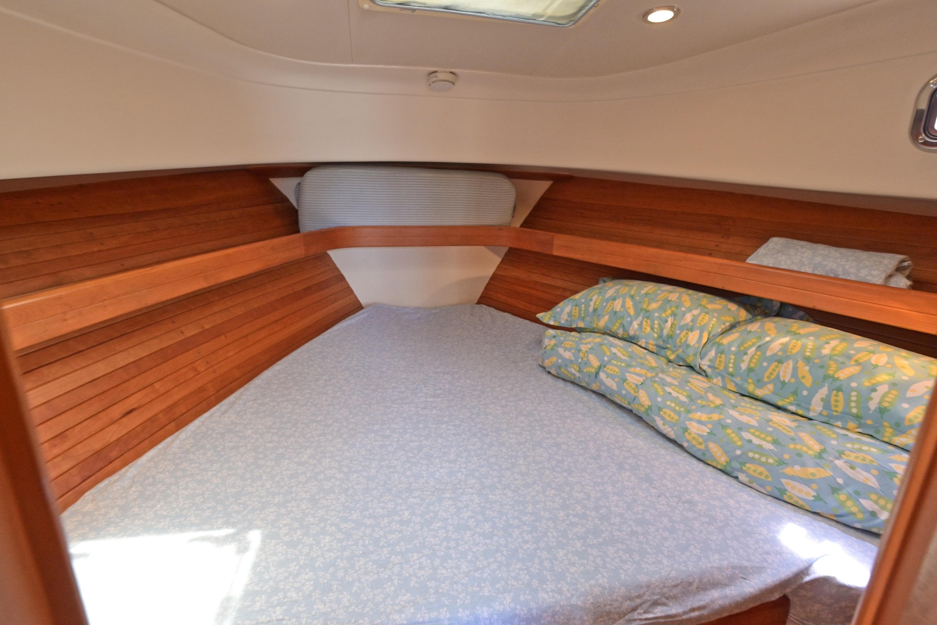 Cozy cabin interior of 2004 Mainship Pilot 34 with wooden accents and patterned bedding.