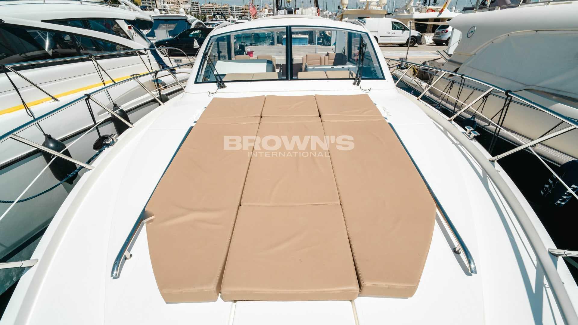 2012 Sealine SC42 yacht with sunbathing deck, docked at marina.