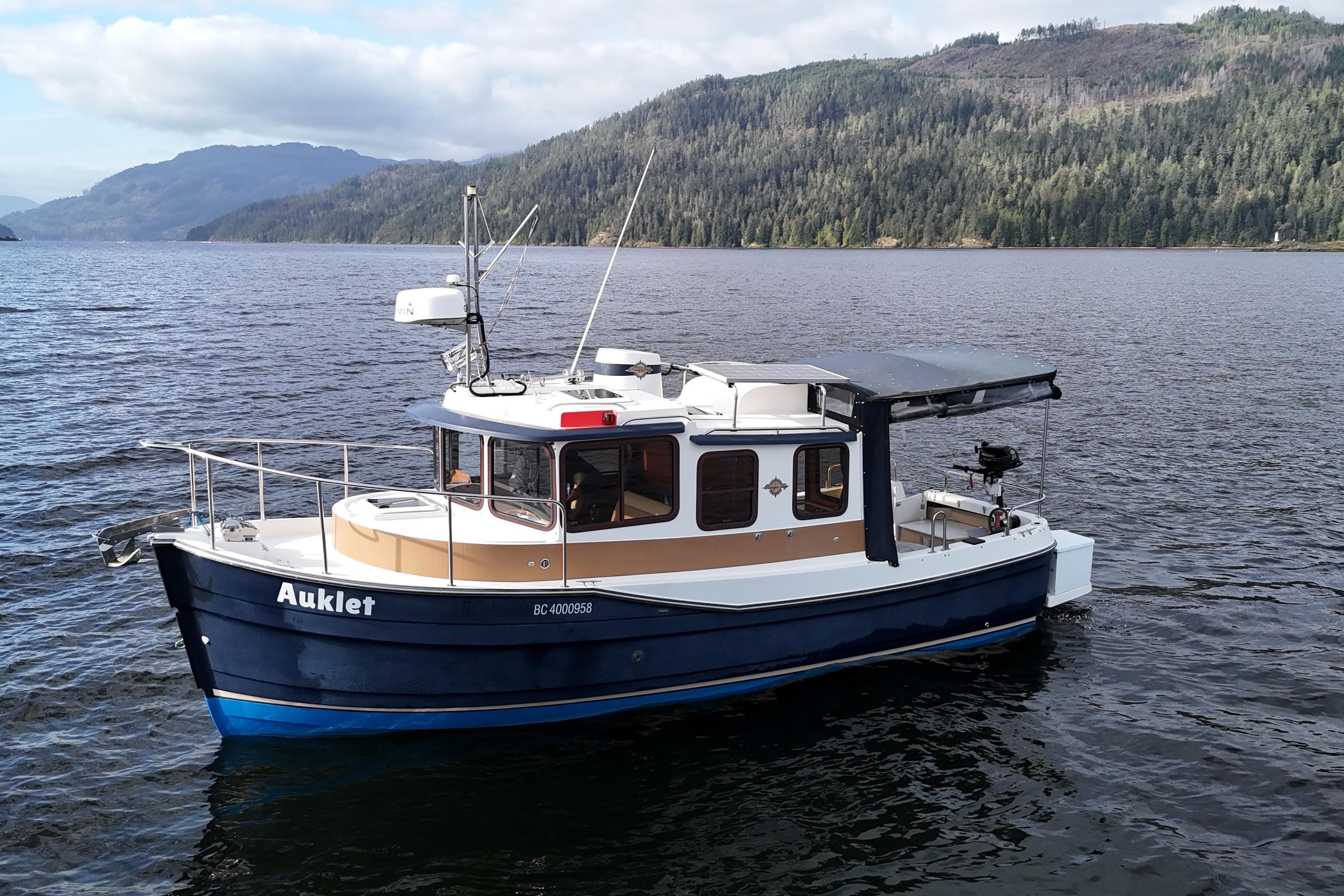 2013 Ranger Tugs R-25 SC boat on a scenic lake with forested hills.