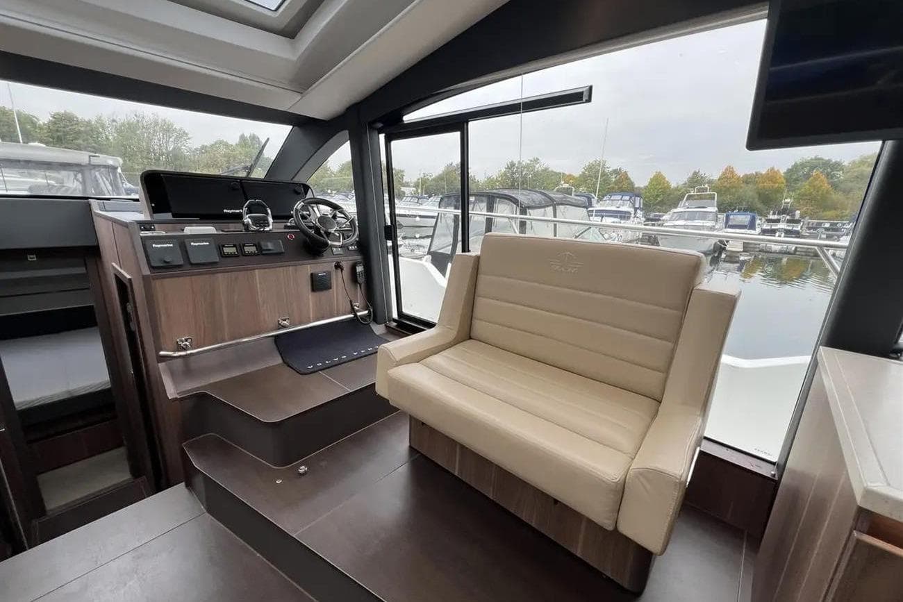 2019 Sealine C430 yacht interior with helm station and seating, overlooking marina.