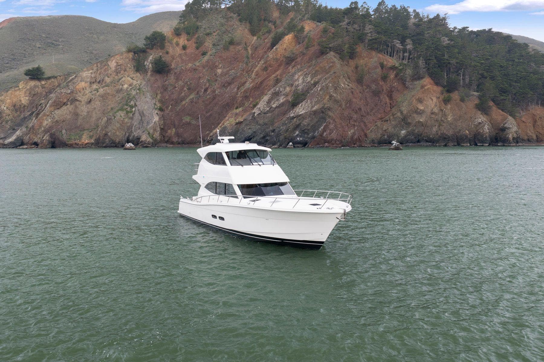 2014 Maritimo M50 yacht on calm water with rocky hillside backdrop.