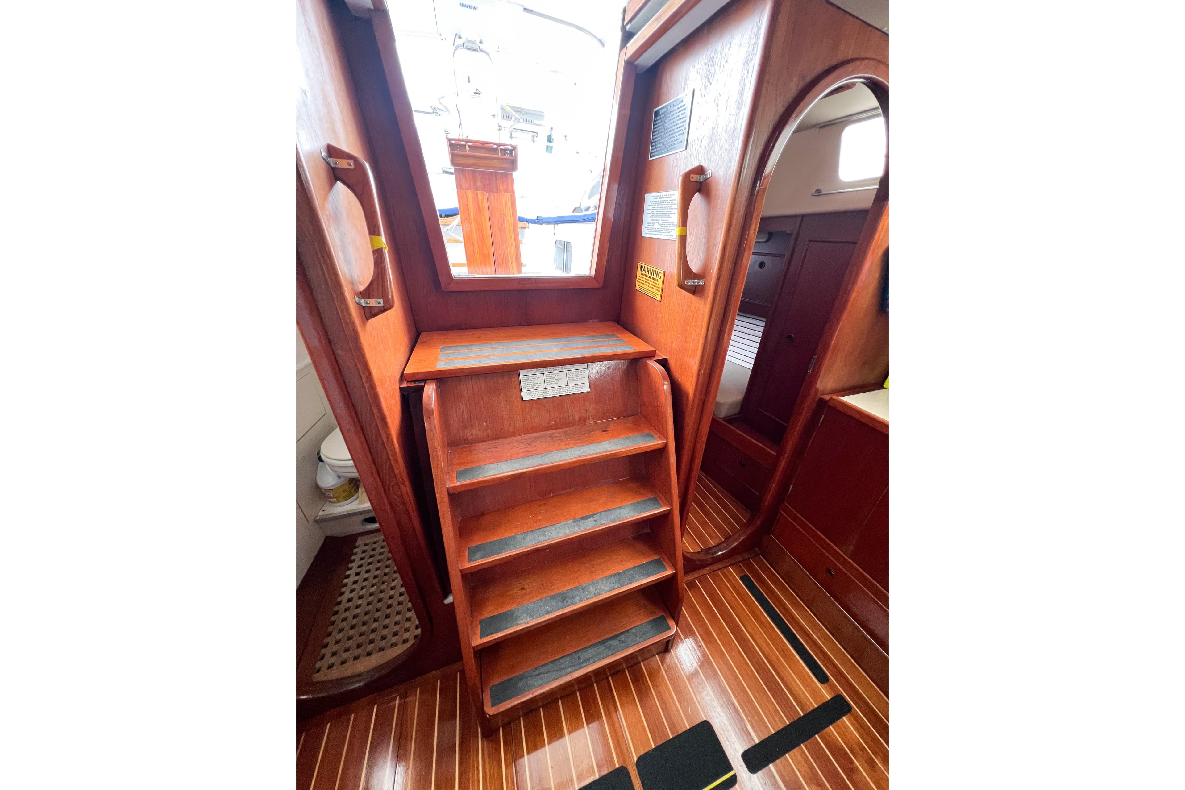Interior of 1984 Trintella 42 sailboat with wooden stairs and cabin entrance.