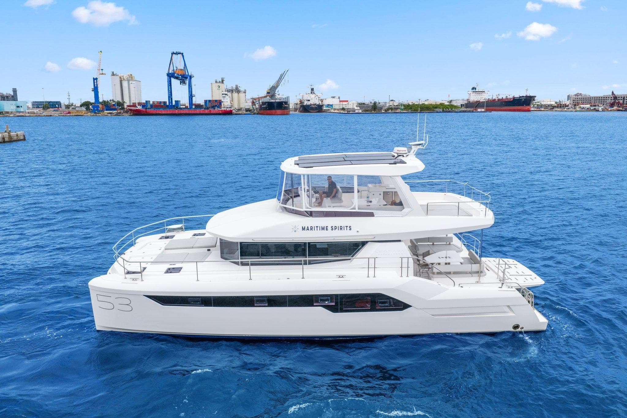 2025 Leopard 53 Powercat yacht cruising in a harbor with industrial background.