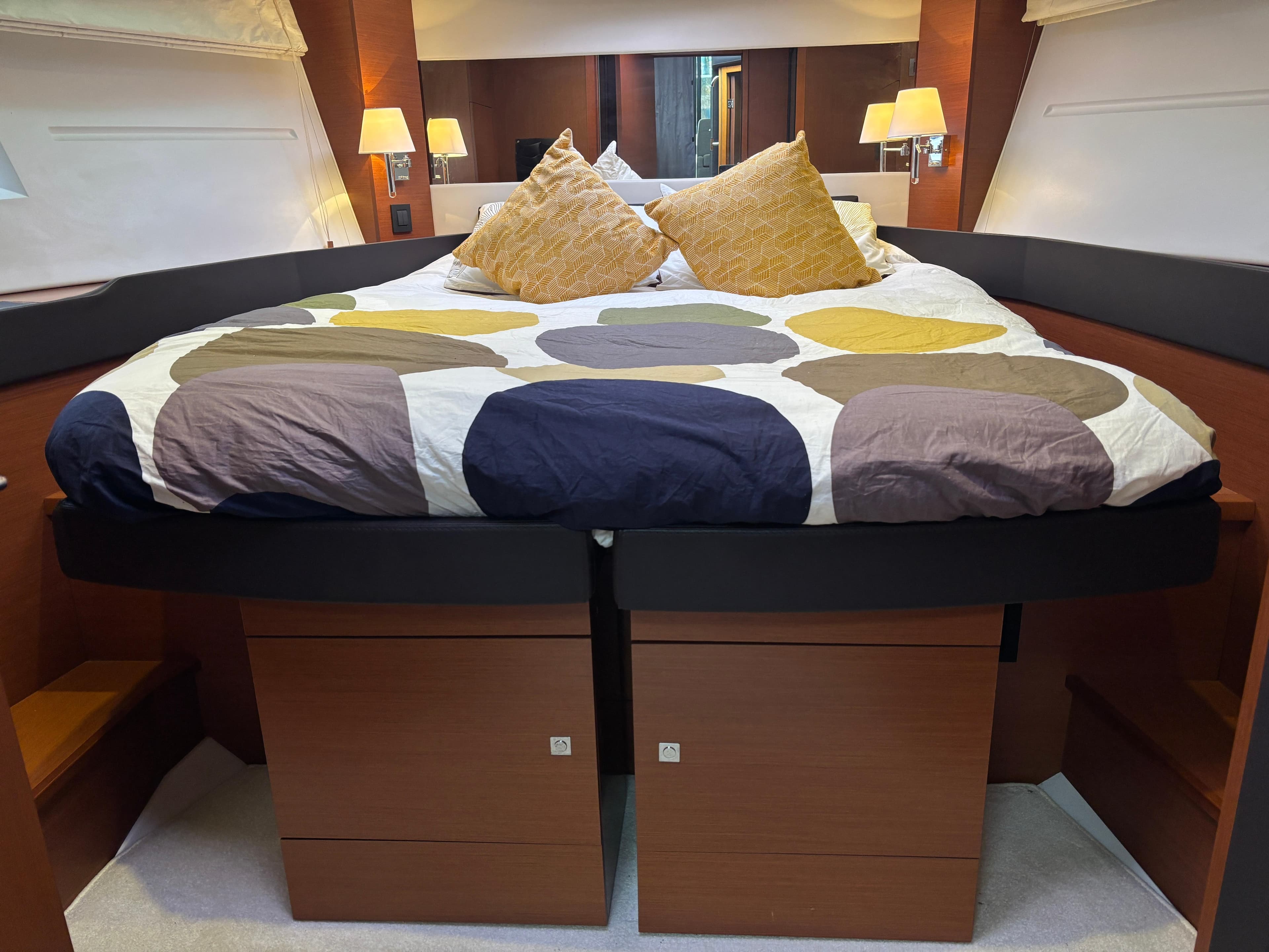 Luxurious bedroom interior of 2014 Jeanneau NC 14 yacht with modern bedding and lighting.