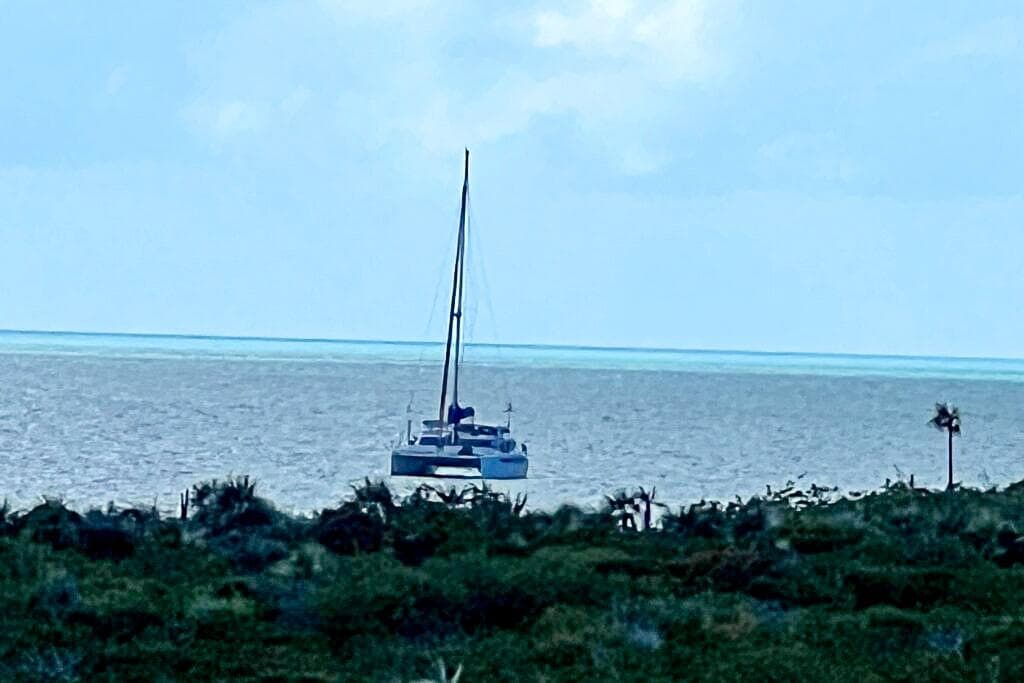 Sailboat Dolphin 460, 2006 model, on calm ocean near lush green coastline.