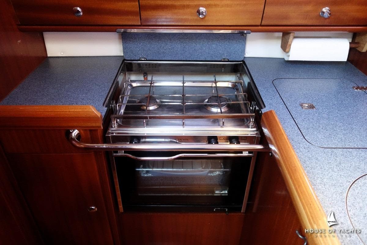 Compact kitchen area in a 2003 Bavaria 32 yacht with a stainless steel stove.