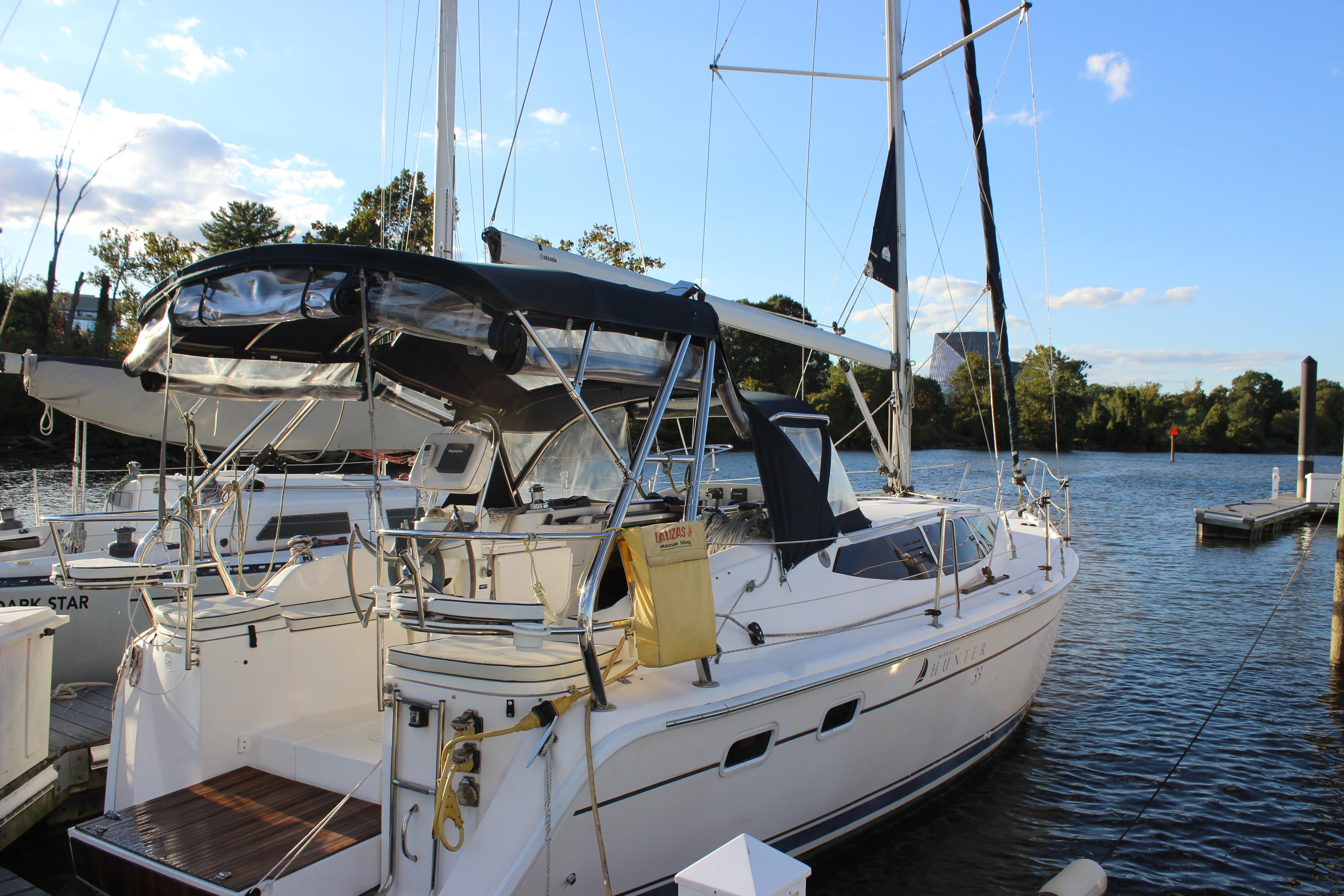 2014 Hunter 33 sailboat docked on a sunny day by the water.