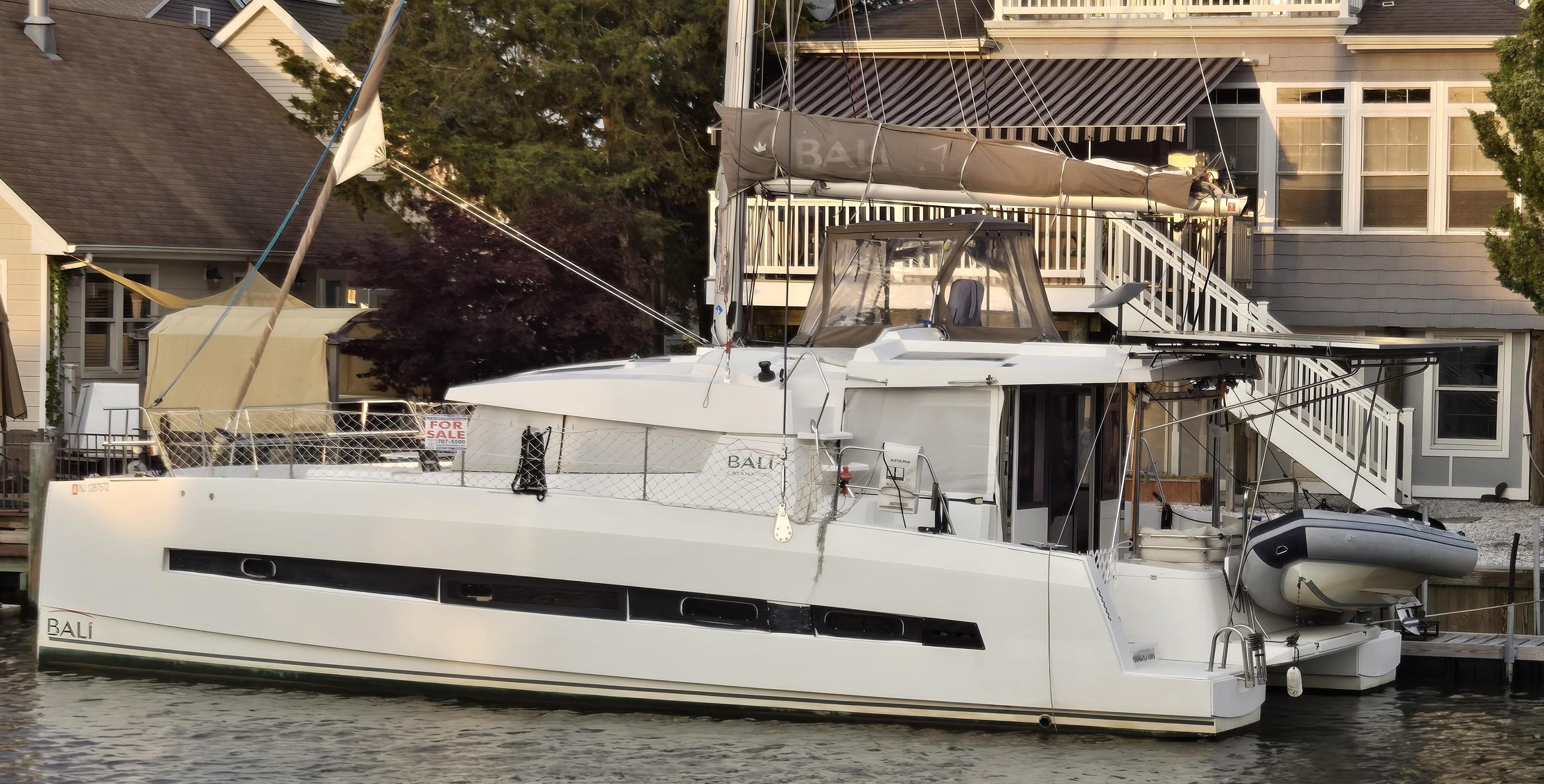 2018 Bali 4.1 Catamaran docked near waterfront homes.