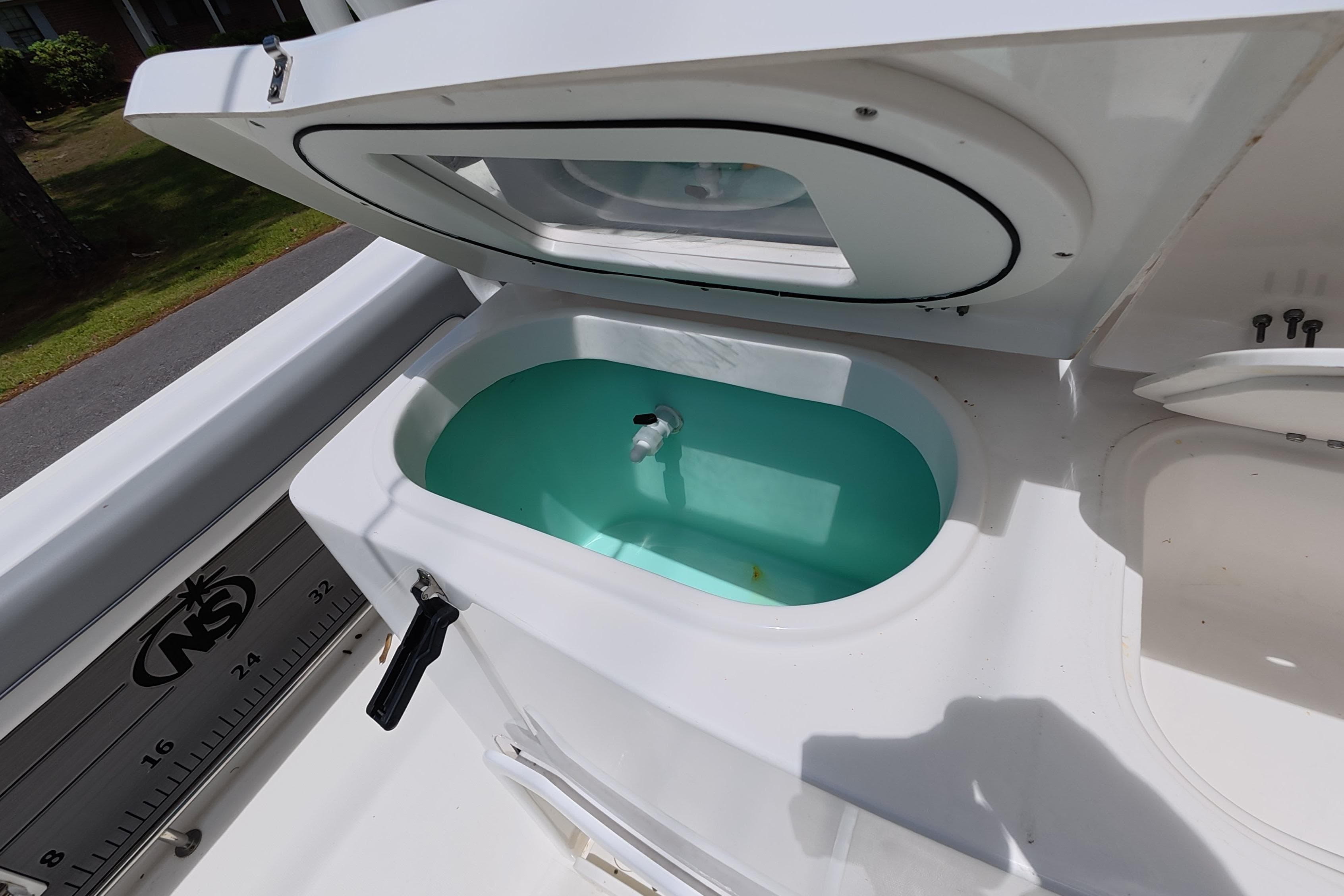 Livewell on 2021 NauticStar 28 XS boat, open lid, filled with water.