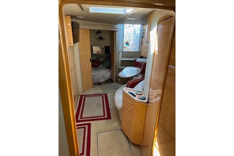 Interior of 1997 Sea Ray 450 Sundancer yacht, featuring cozy seating and elegant wood finishes.