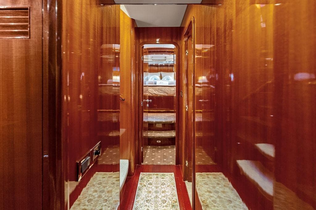 Luxurious wooden interior hallway of a 2005 Horizon 82 yacht, leading to a cozy bedroom.