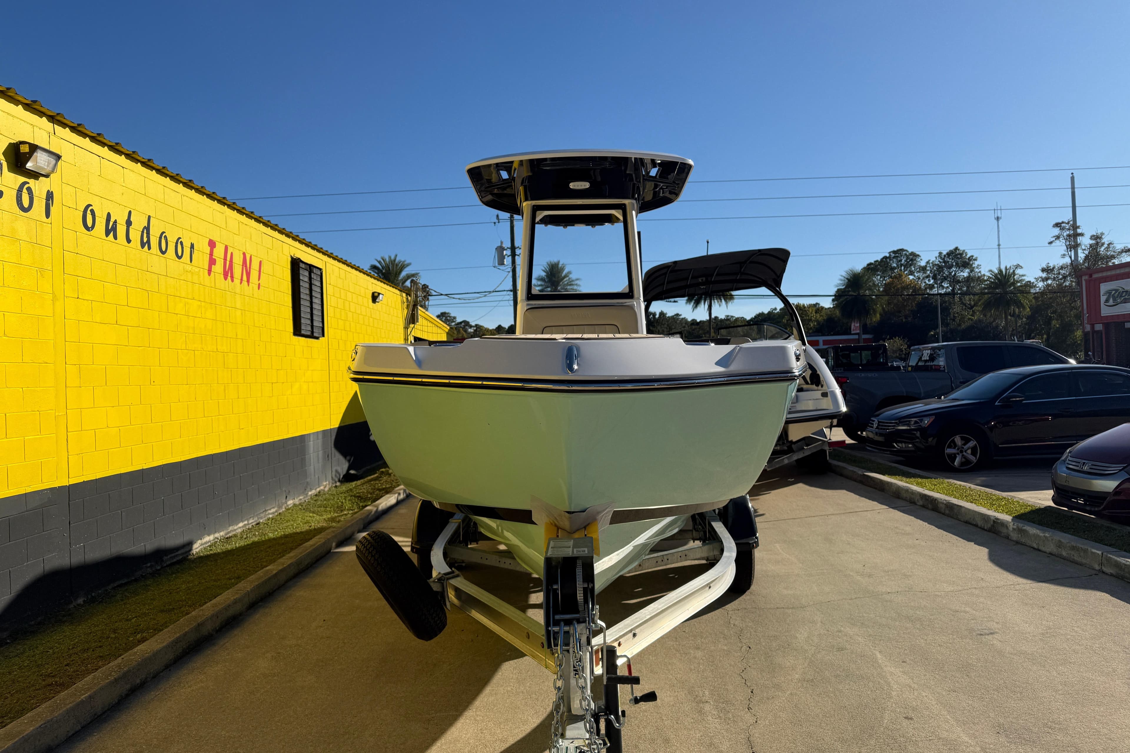2026 Yamaha Boats 222 FSH Sport E on trailer, parked outdoors near a yellow building.