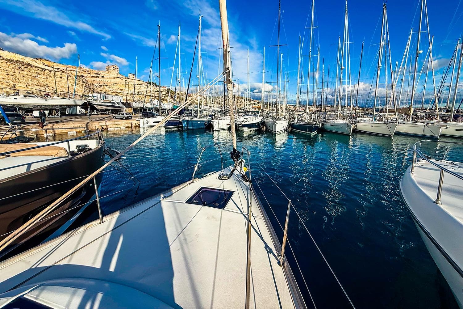 Dufour 460 Grand Large 2019 yacht docked in a sunny marina with clear blue skies.