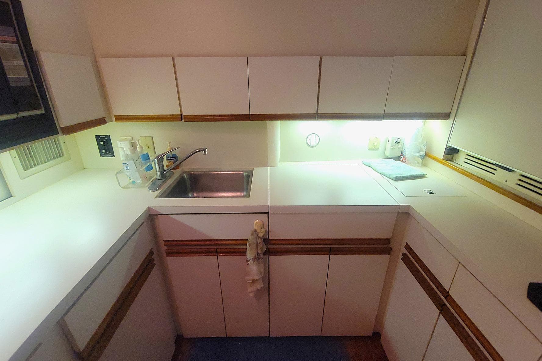 1989 Bertram 50 Convertible yacht kitchen with sink, white cabinets, and countertop.
