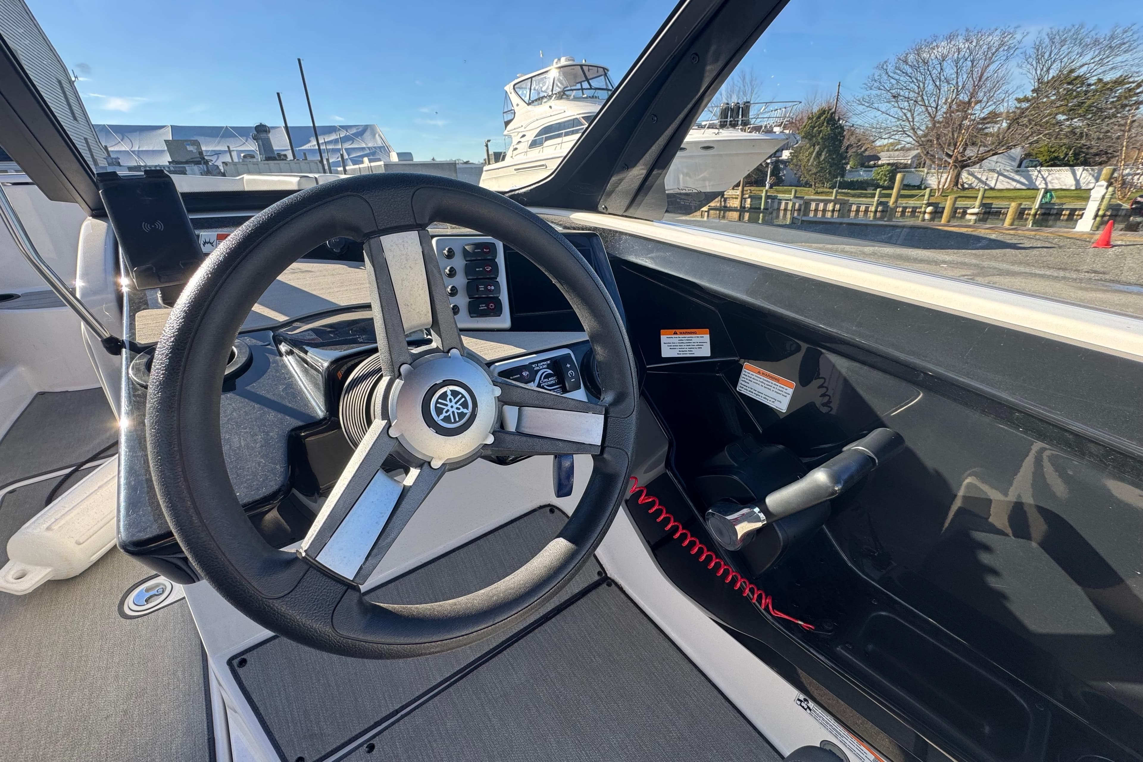 2023 Yamaha Boats AR220 steering wheel and dashboard in a marina setting.