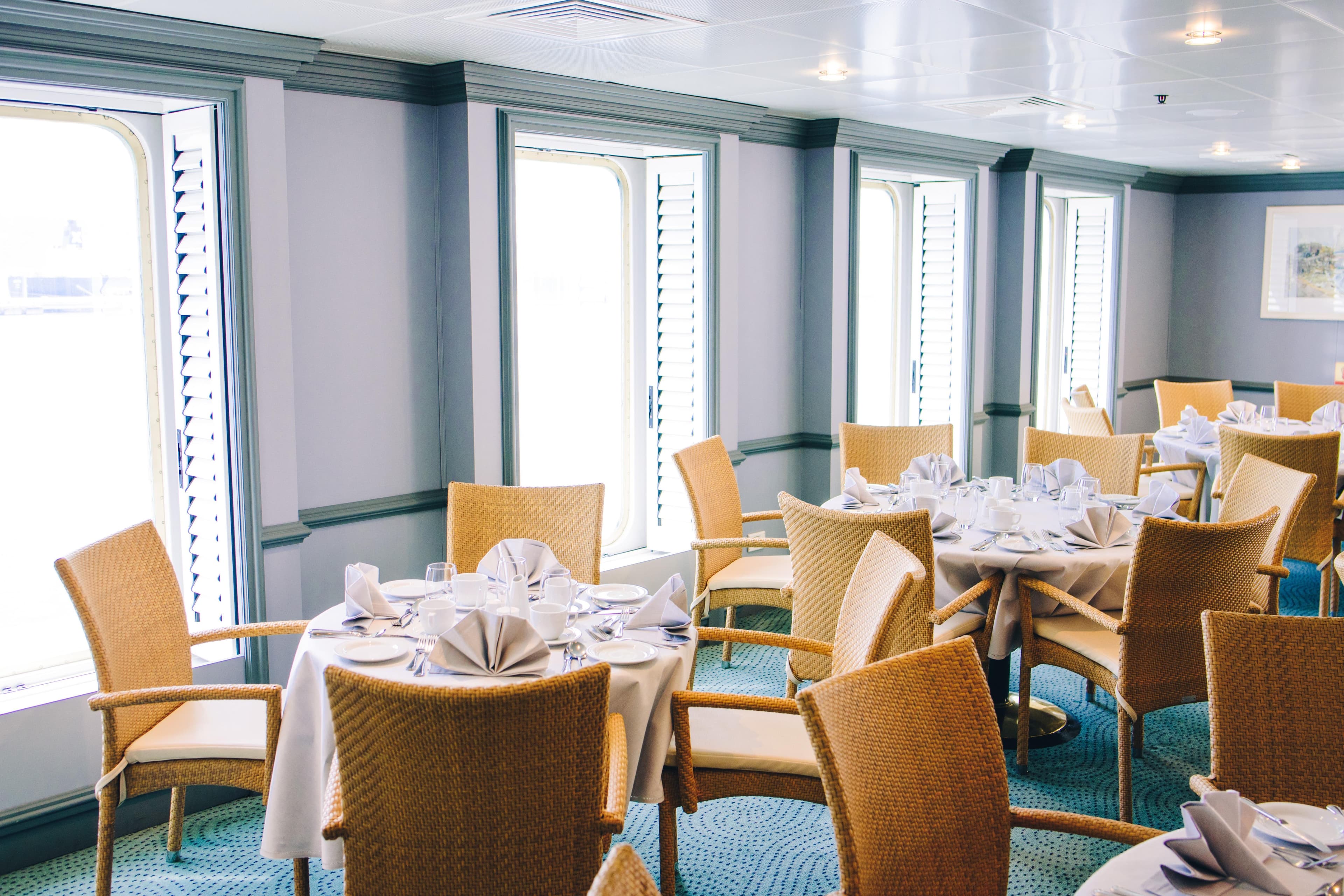 Elegant dining area on 1996 MINERVA cruise ship with neatly set tables and wicker chairs.