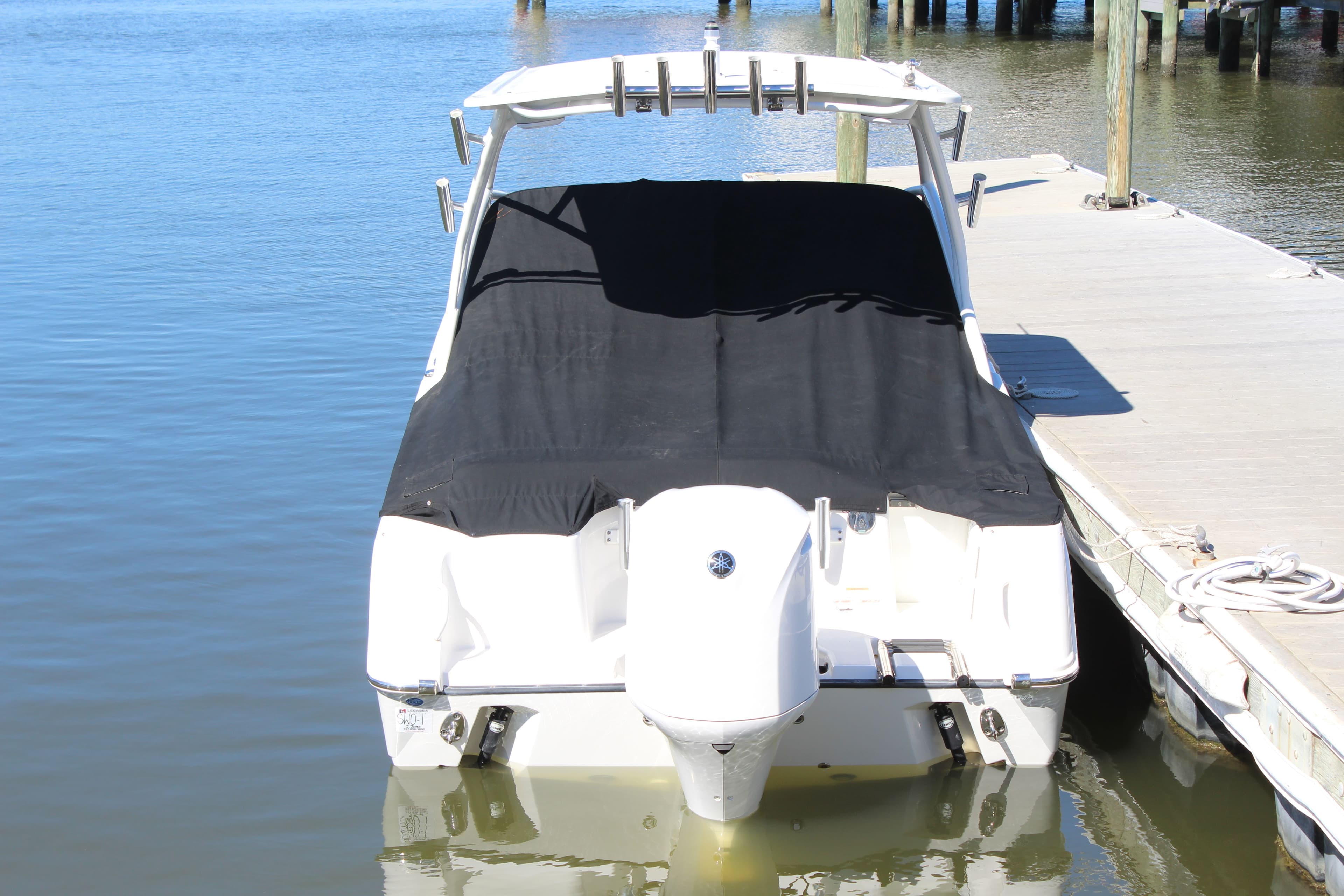 2020 Edgewater 248CX Crossover boat docked with black cover, rear view.