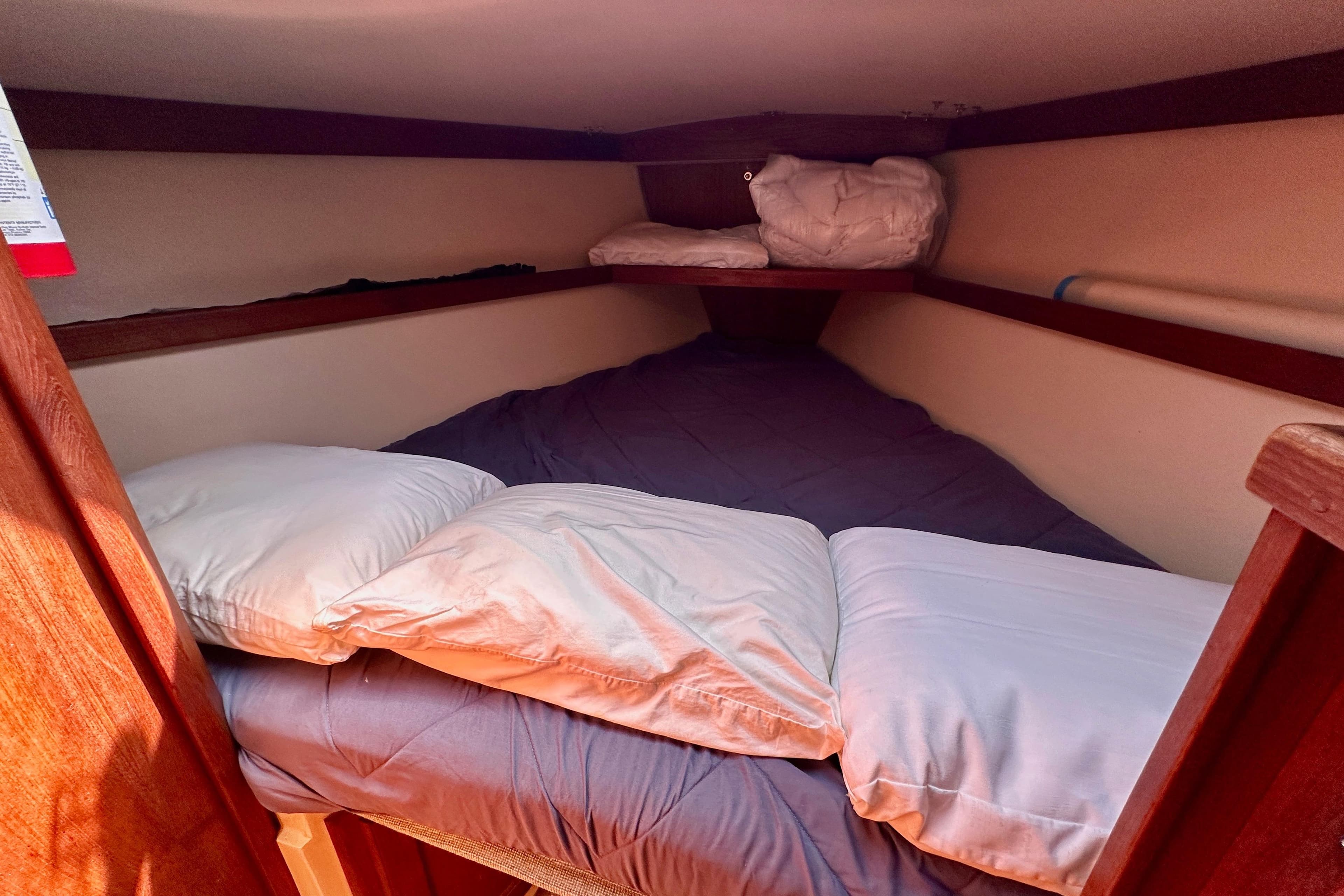Cozy sleeping quarters in a 1989 Catalina 36 sailboat cabin with pillows and bedding.