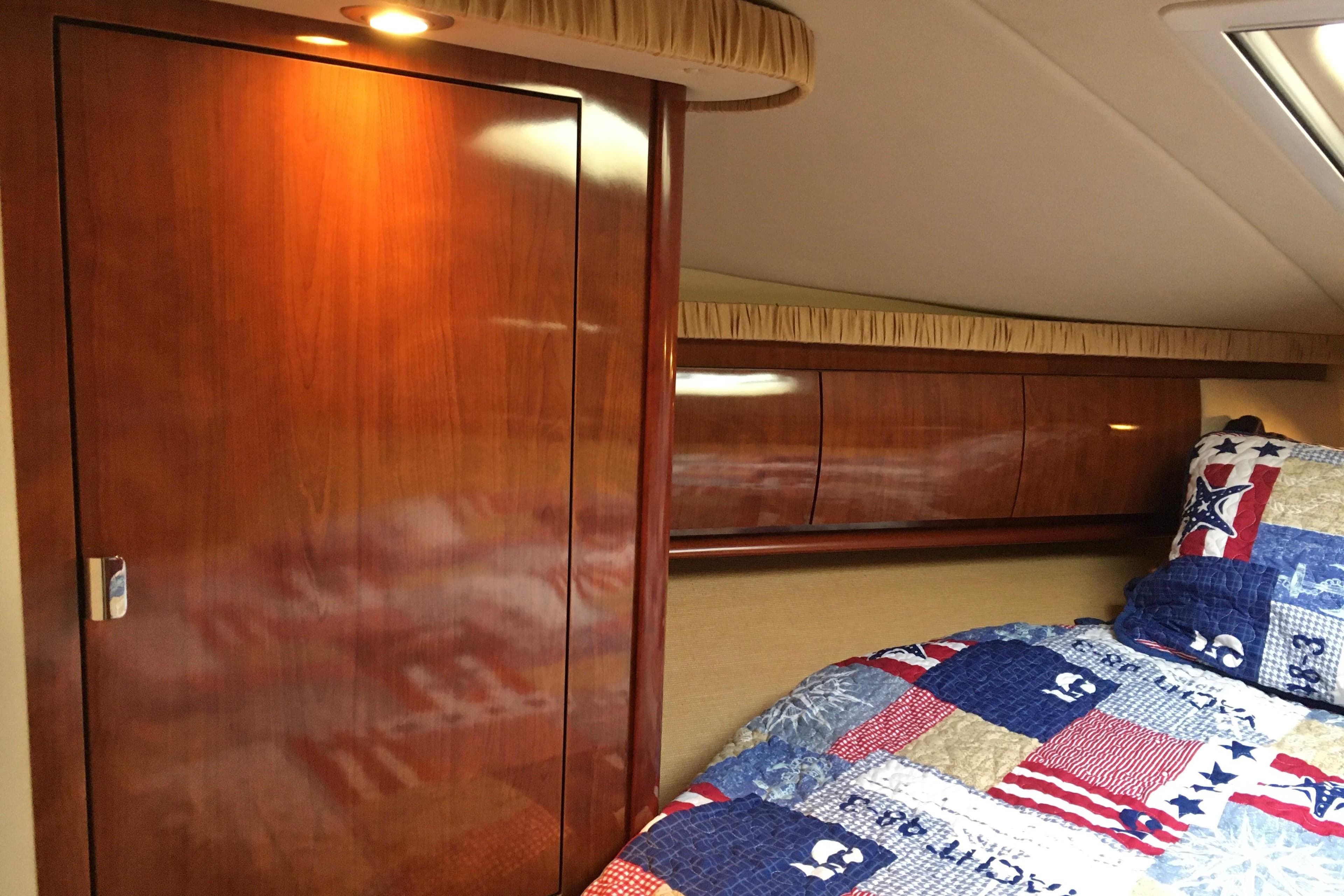 Luxurious 2005 Sea Ray 420 Sundancer cabin with wooden cabinetry and nautical-themed bedding.