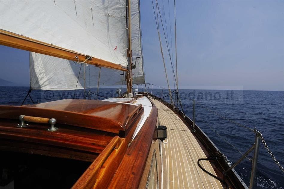 1964 Sangermani Yawl sailing on open sea with wooden deck and white sails.