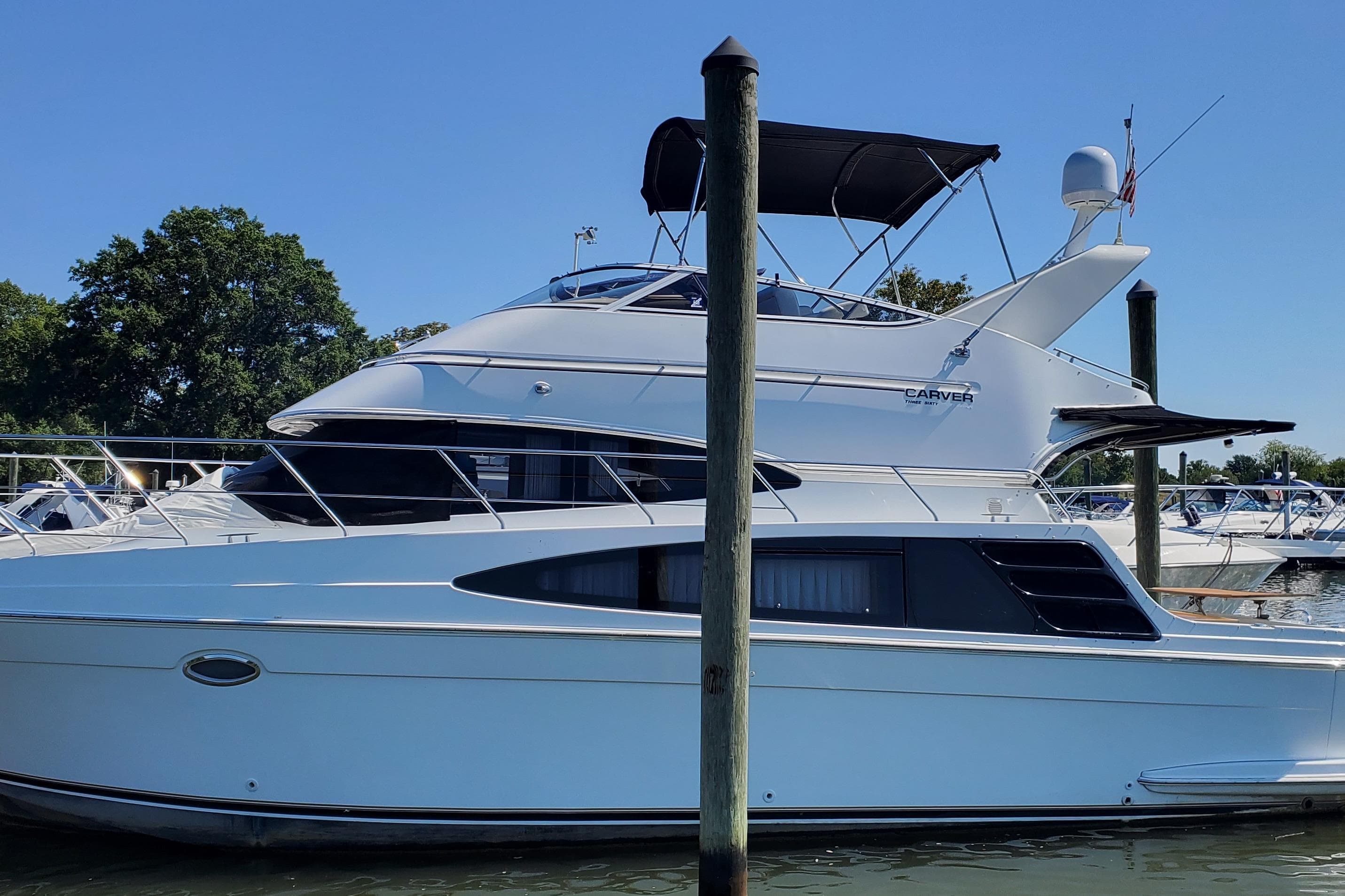 2003 Carver 36 Super Sport yacht docked at marina under clear blue sky.