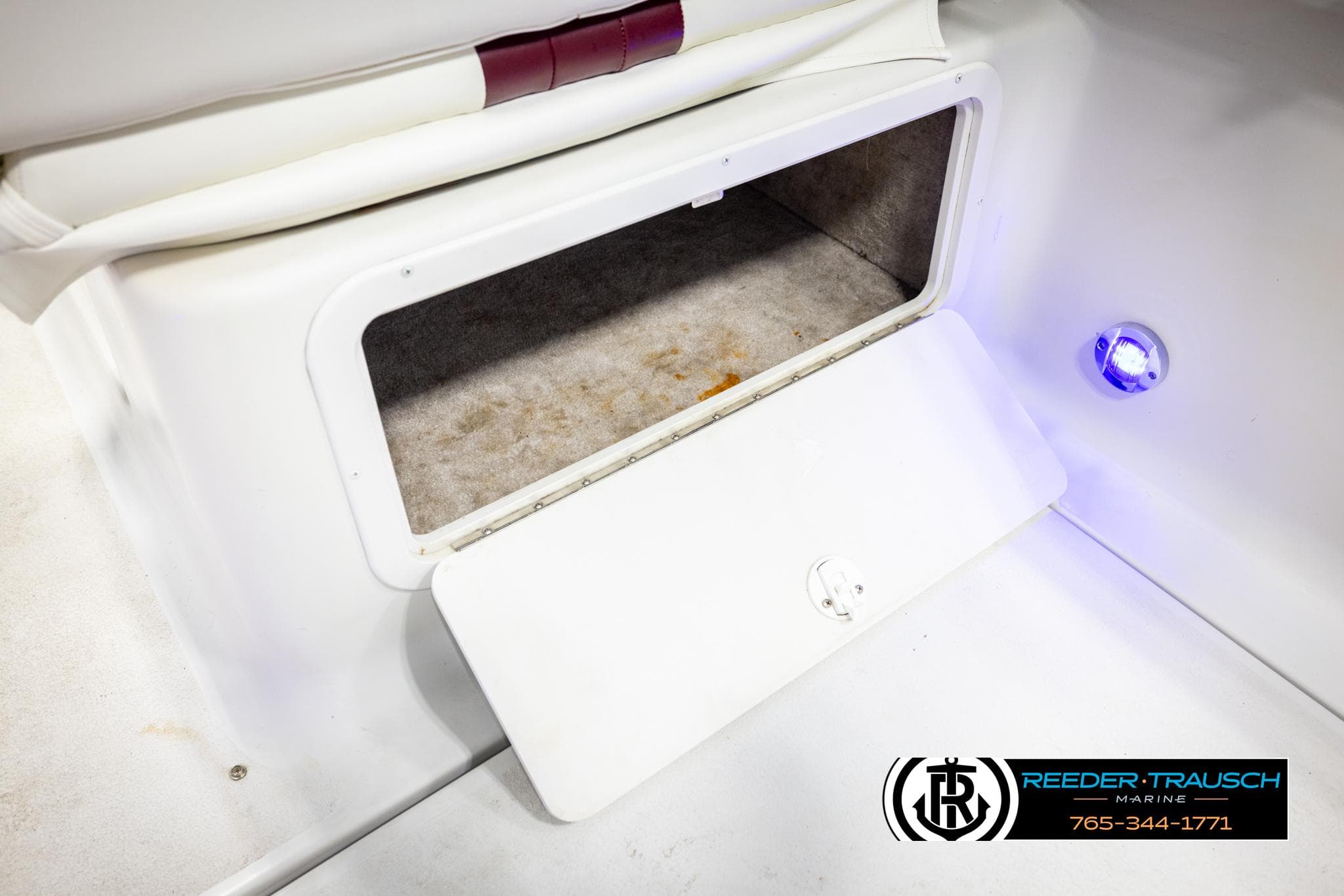 Open storage compartment on 1999 Crownline 242 CR boat with blue LED light.