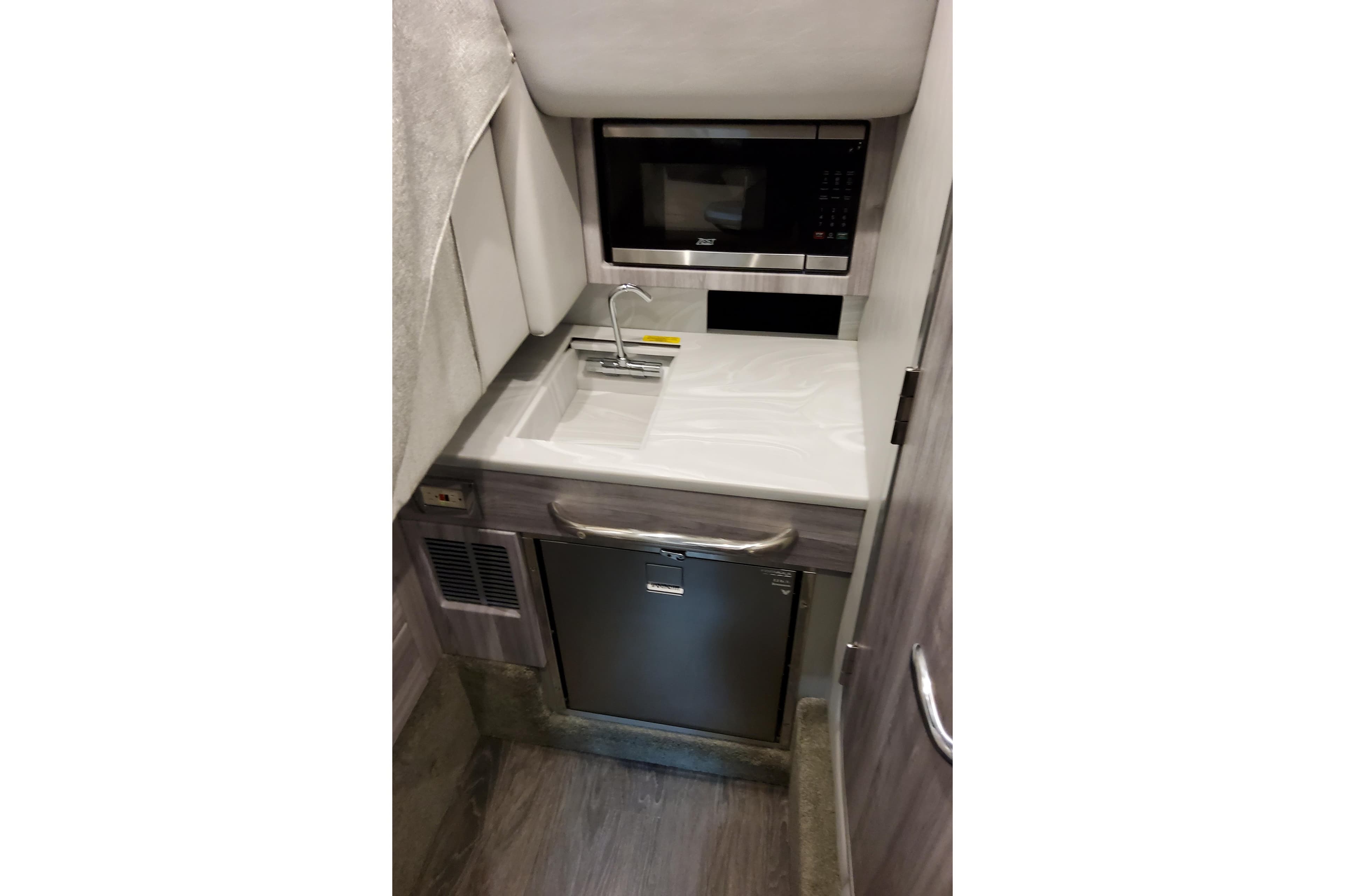 Compact kitchenette in 2026 Formula 350 Crossover Bowrider OB with sink, microwave, and fridge.