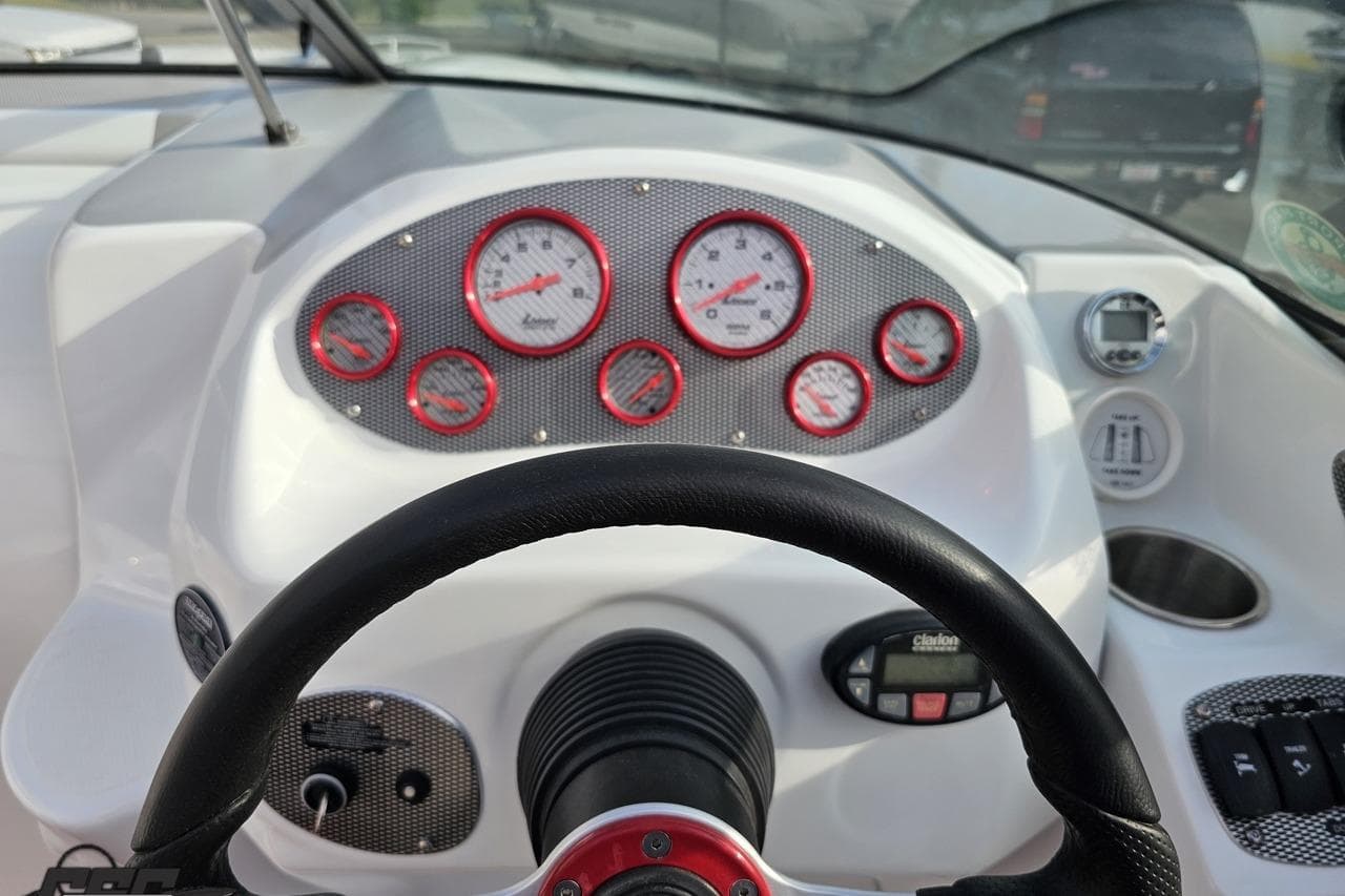 Dashboard of a 2004 Baja 275 boat with red-accented gauges and steering wheel.