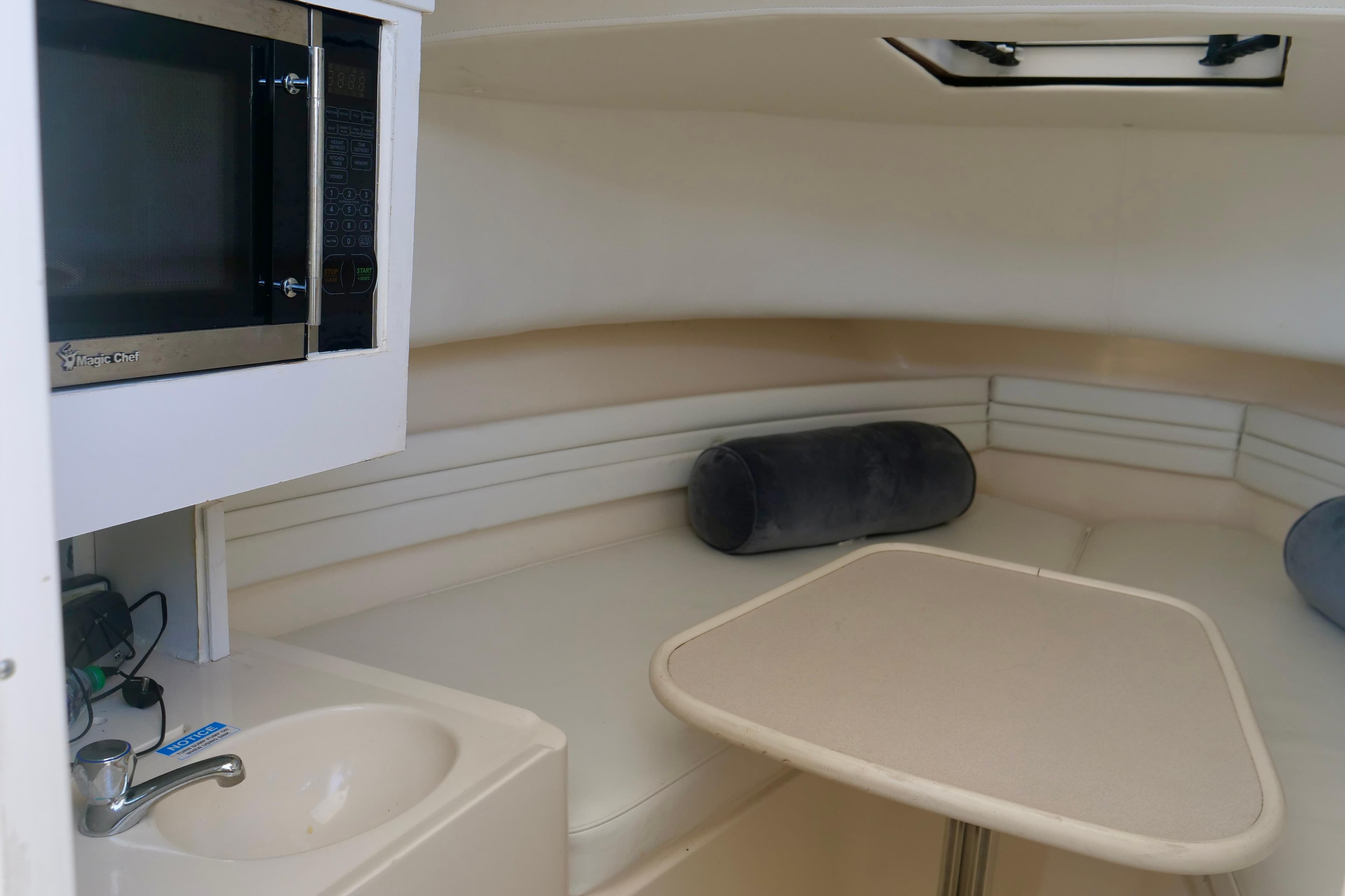 1999 Pursuit 2870 Walkaround cabin interior with microwave, sink, and seating area.