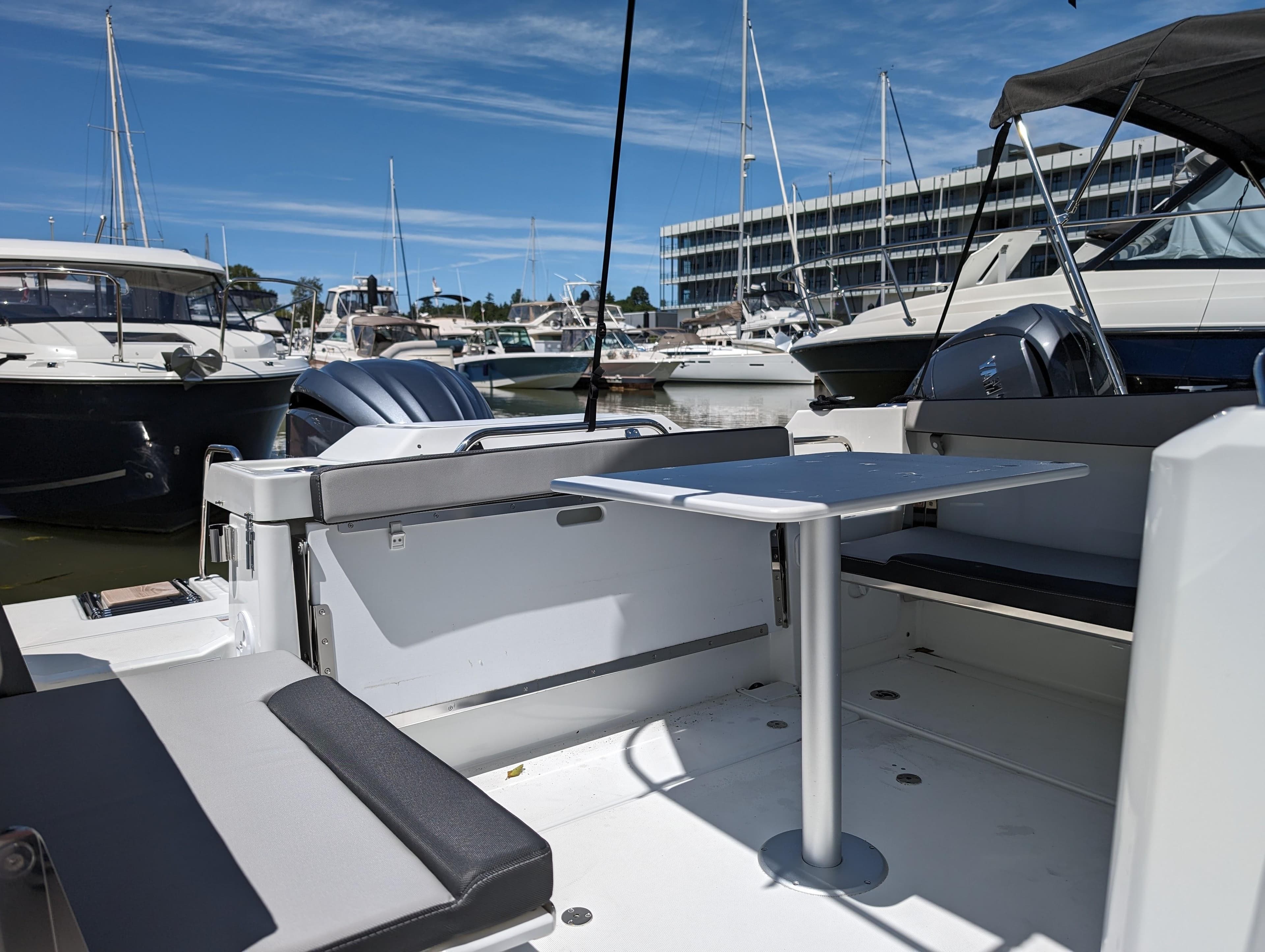2024 Jeanneau NC Sport 795 Series 2 boat interior with seating and table at marina.