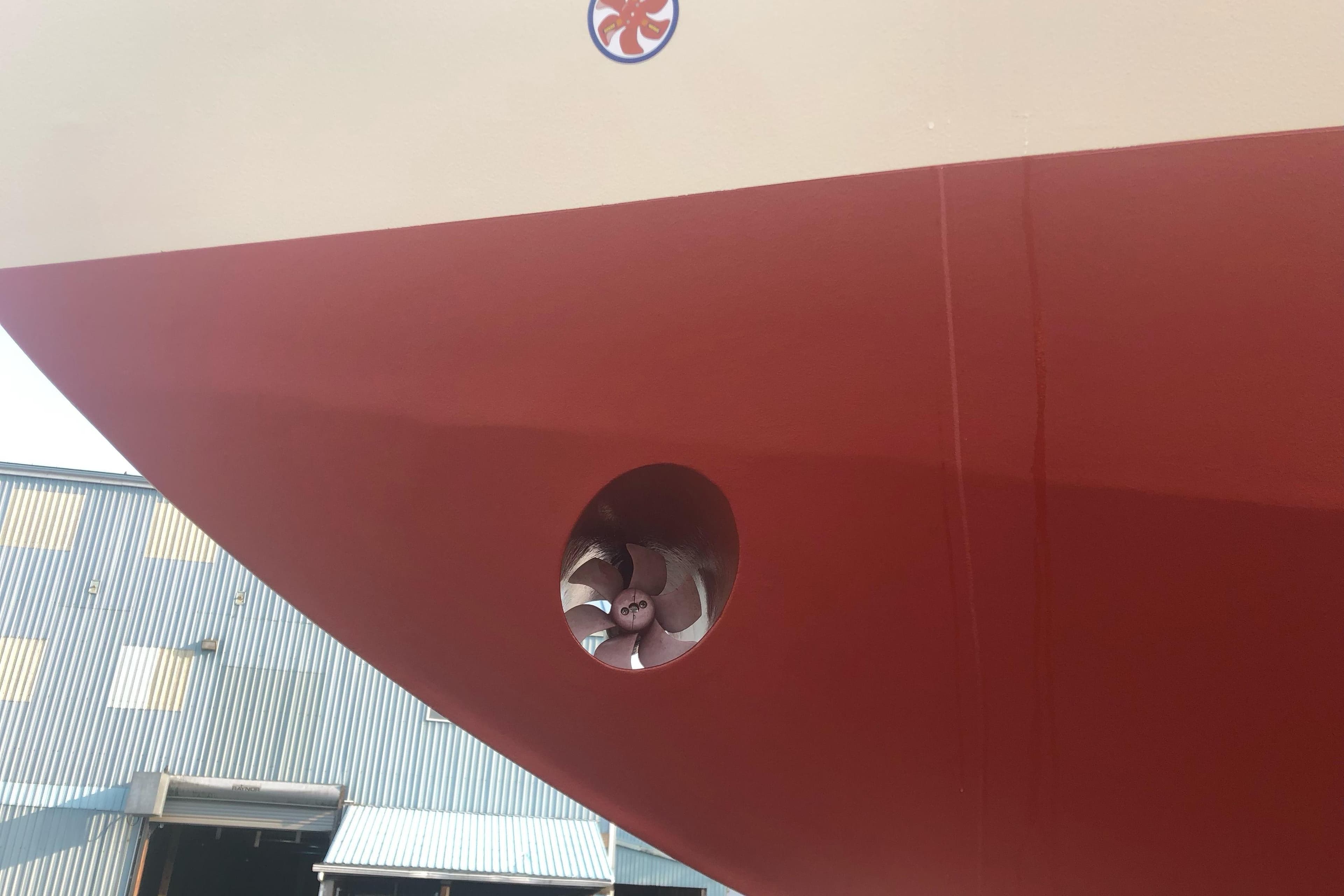 Red hull of 2020 Bruce Roberts 46 Pilothouse with visible bow thruster.