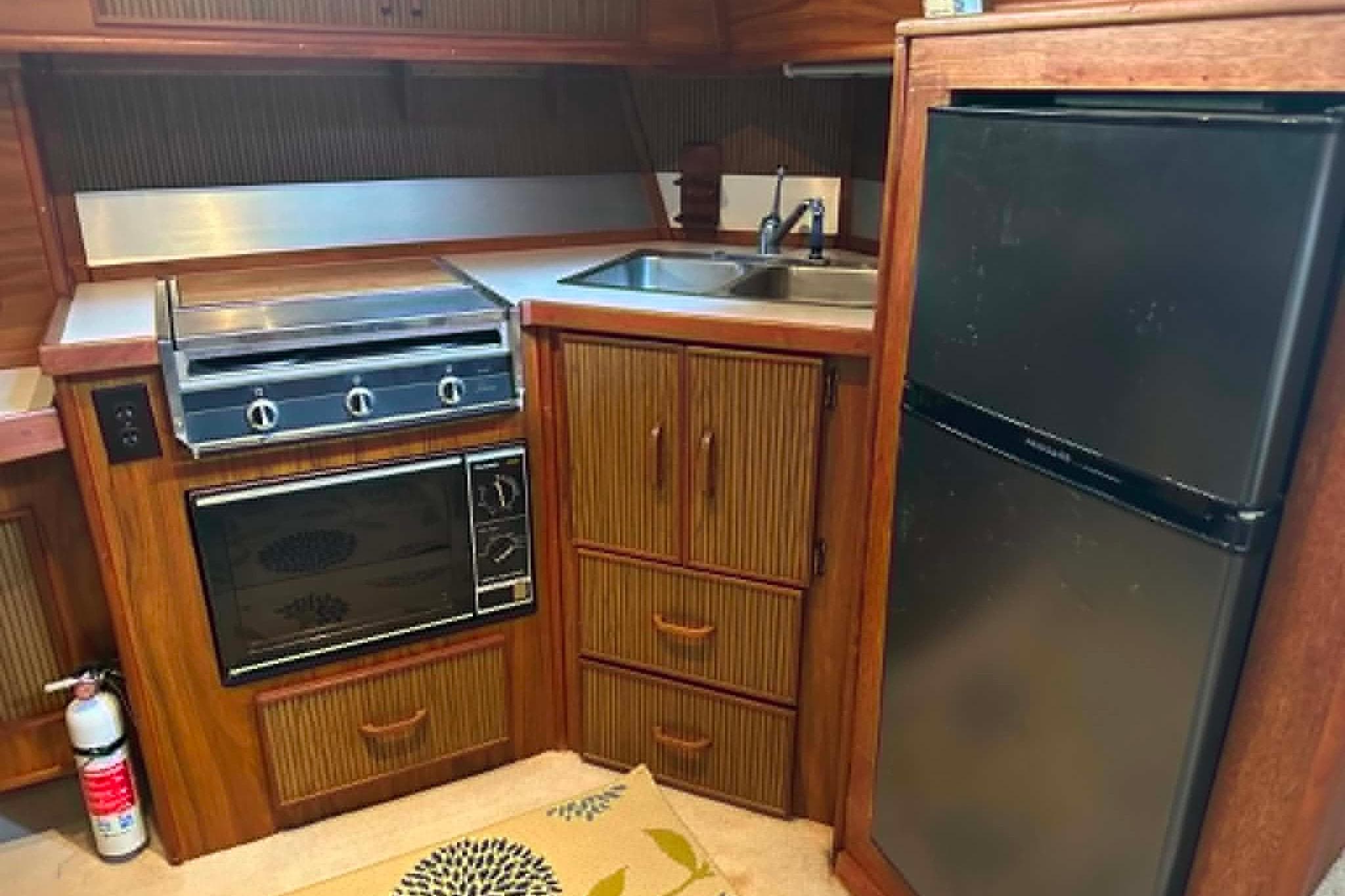 1988 Sea Ray 390 Express Cruiser kitchen with stove, microwave, sink, and refrigerator.