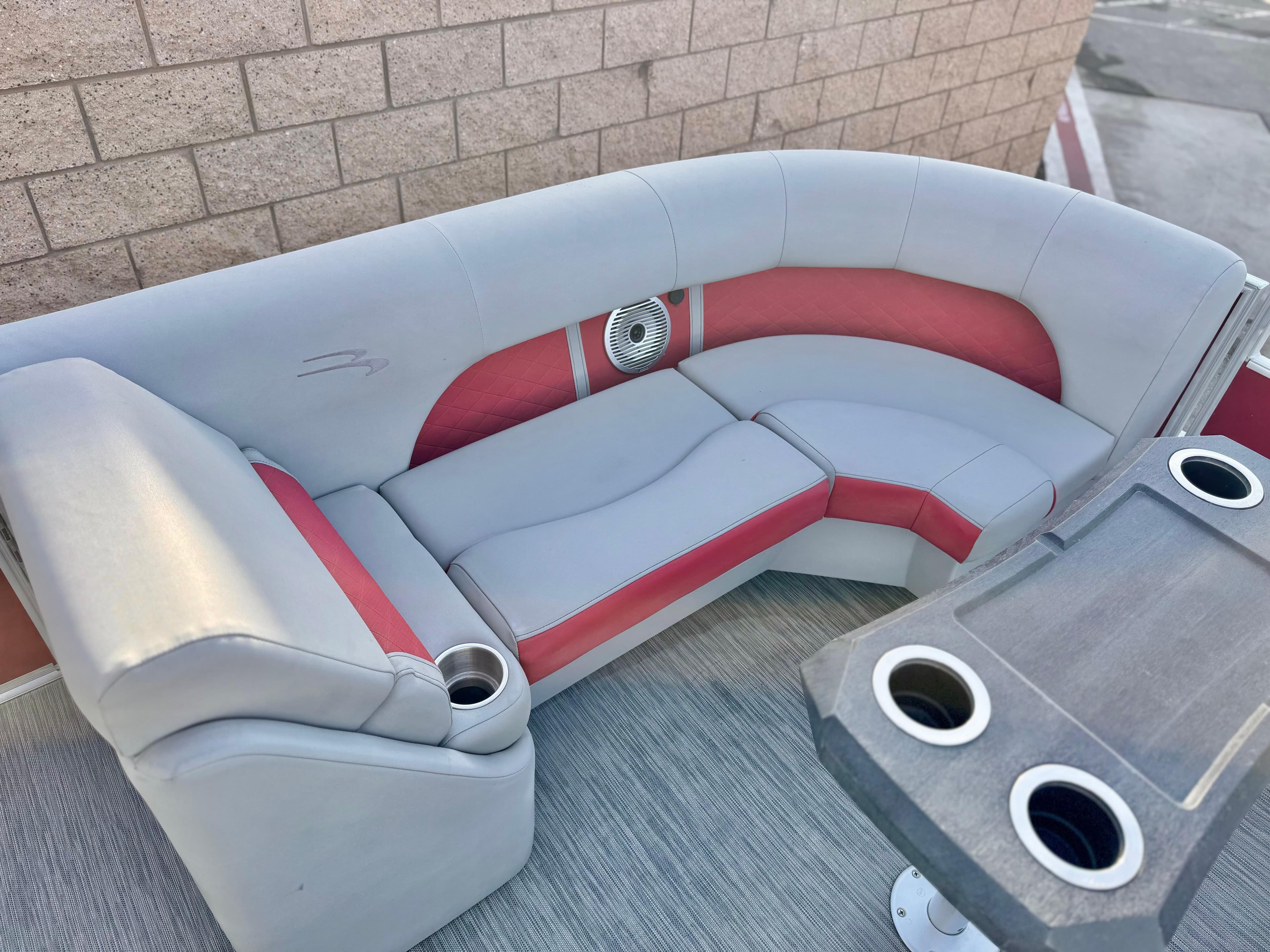 2021 Bennington 23 LS RSD boat seating with red and gray upholstery and cup holders.